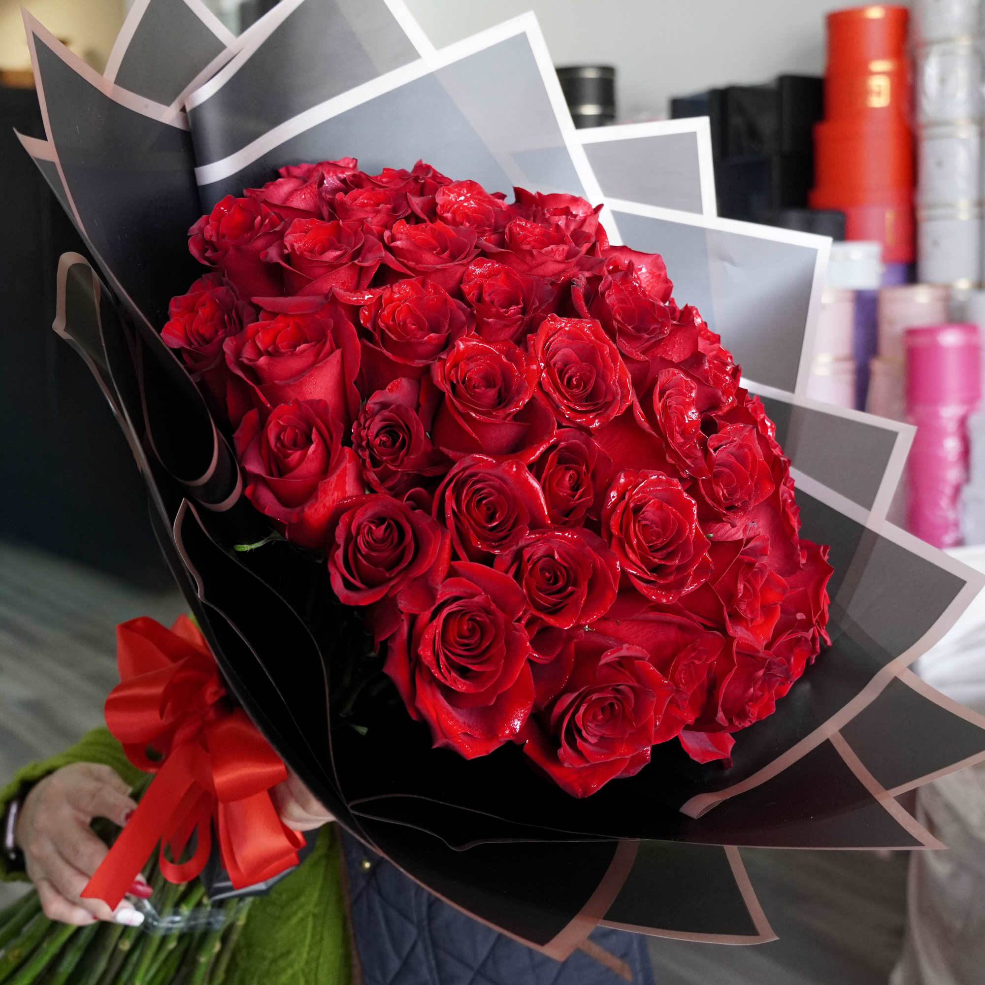 Large bouquet of red roses wrapped in black paper with a red ribbon.