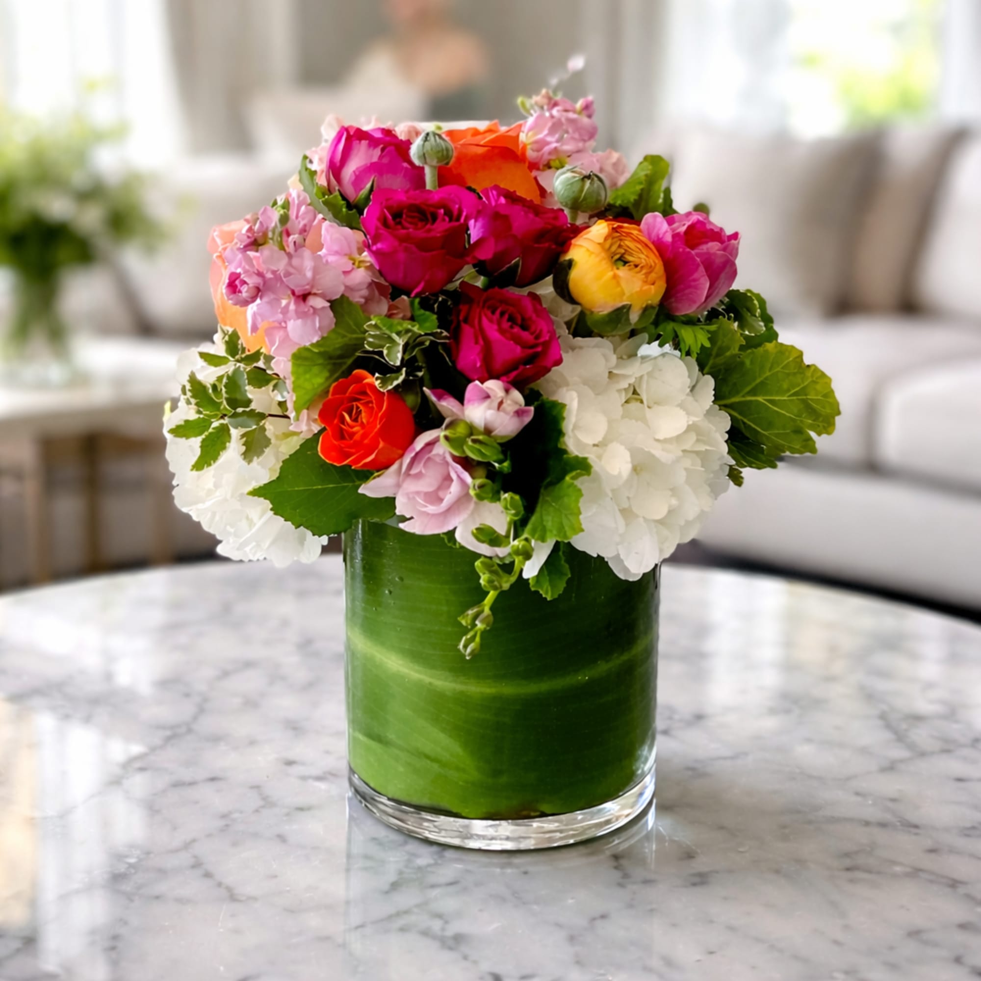 Mixed pink, white, and orange flowers in a green glass vase