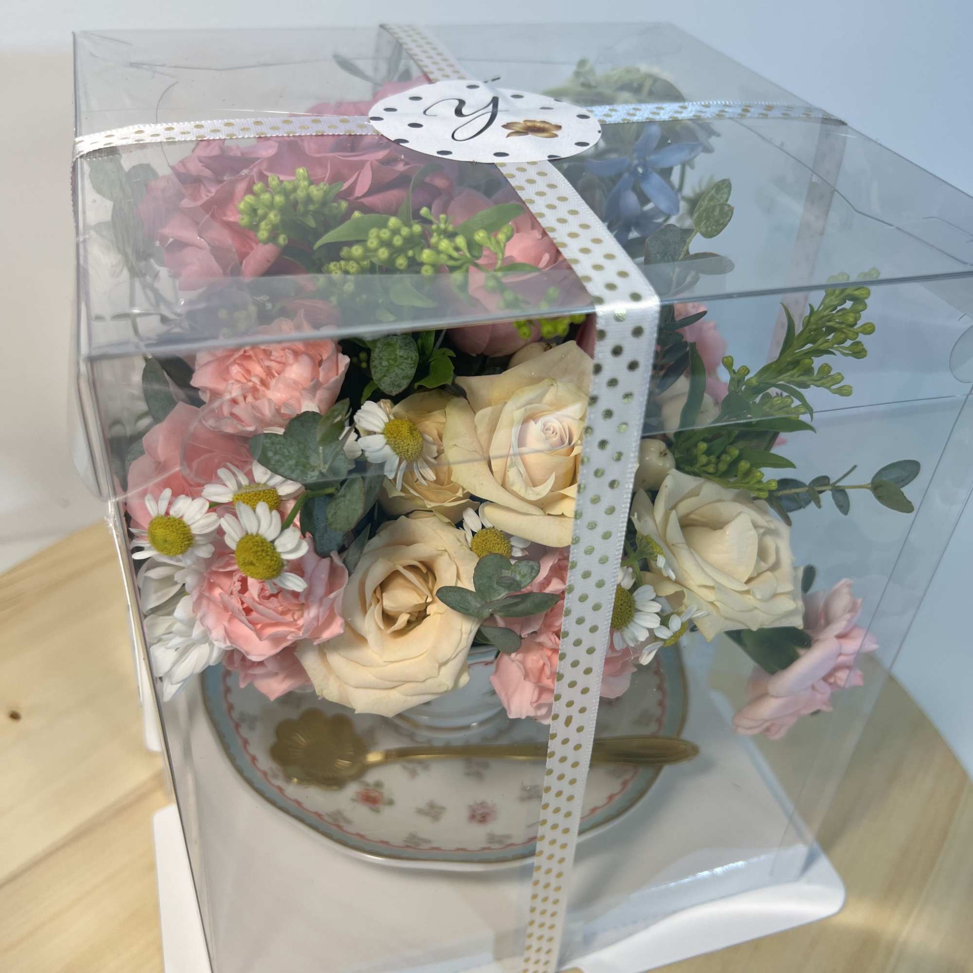A tea cup filled with roses, carnations, and tiny white daisy-like blooms-this