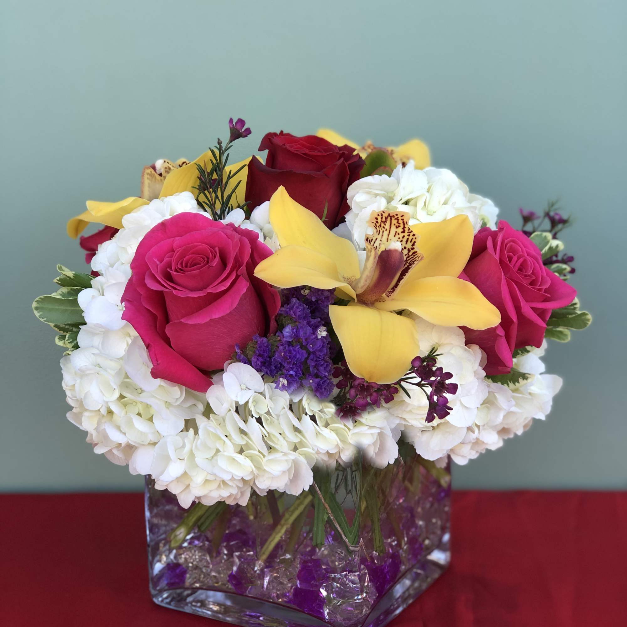 Bouquet of pink and red roses with yellow orchids in a glass vase