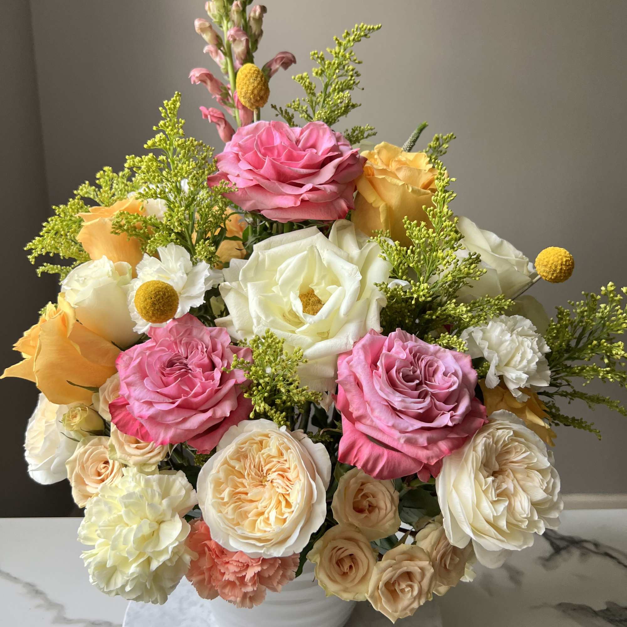 A romantic garden-style arrangement designed in an elegant white ceramic vase featuring