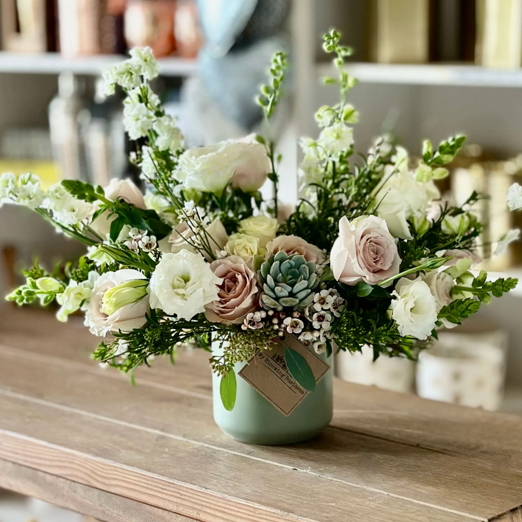 Mixed white and blush flowers arranged in a mint vase