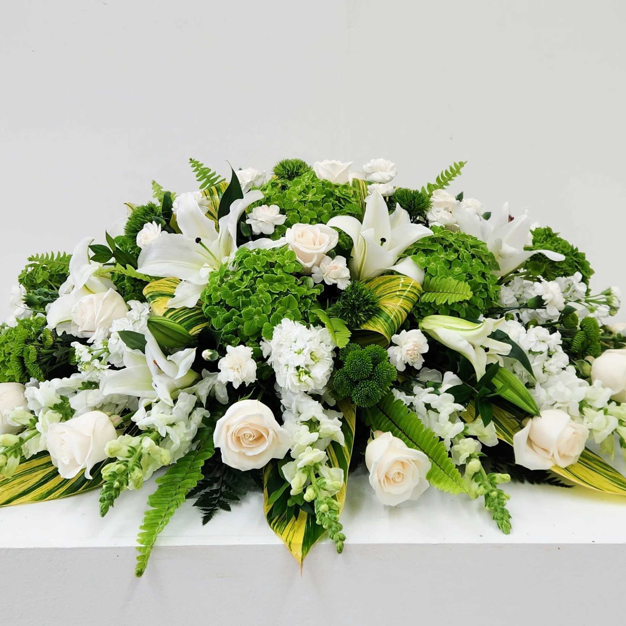 A calm, formal spread of white roses and lilies set against vivid