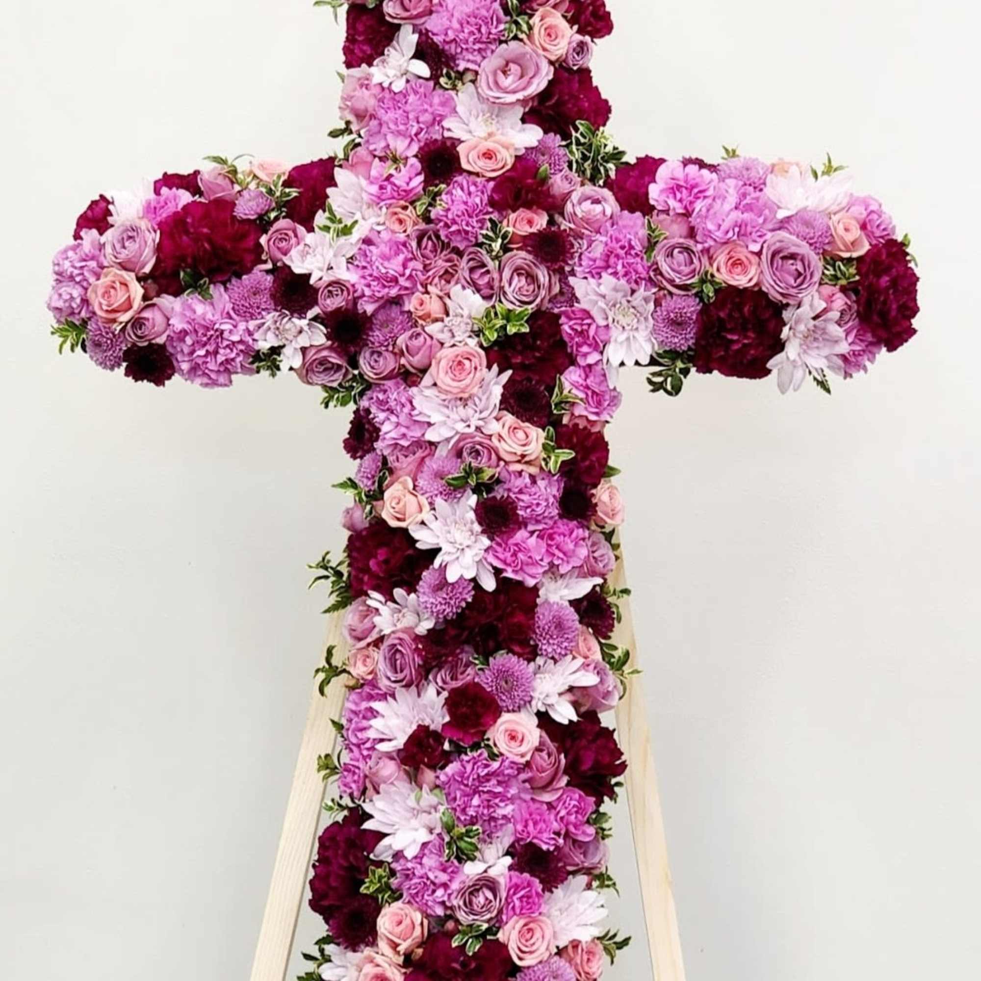 A large, dignified floral cross in soft pinks, lavender, whites and deep
