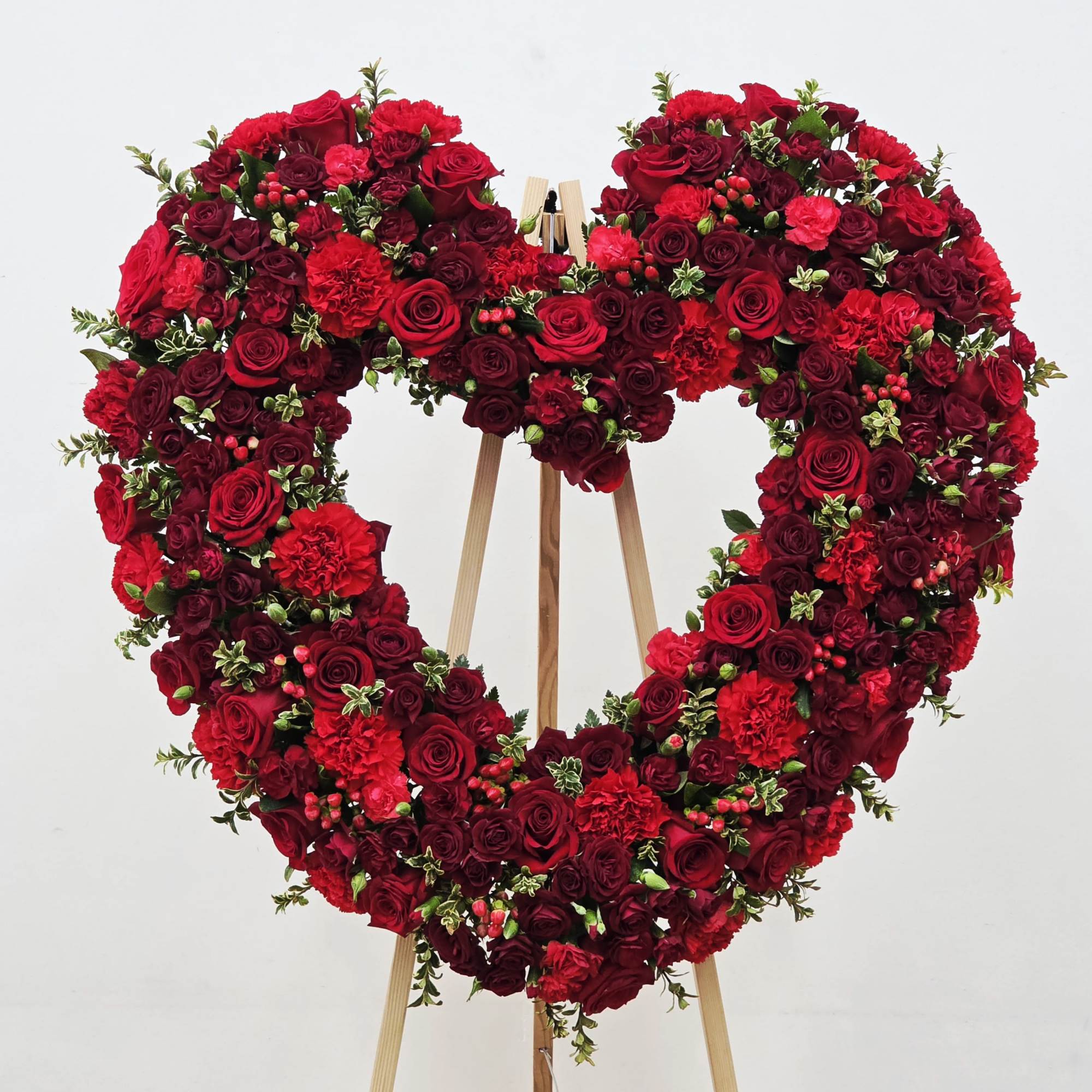 A dense heart of red and burgundy roses, accented with bright red
