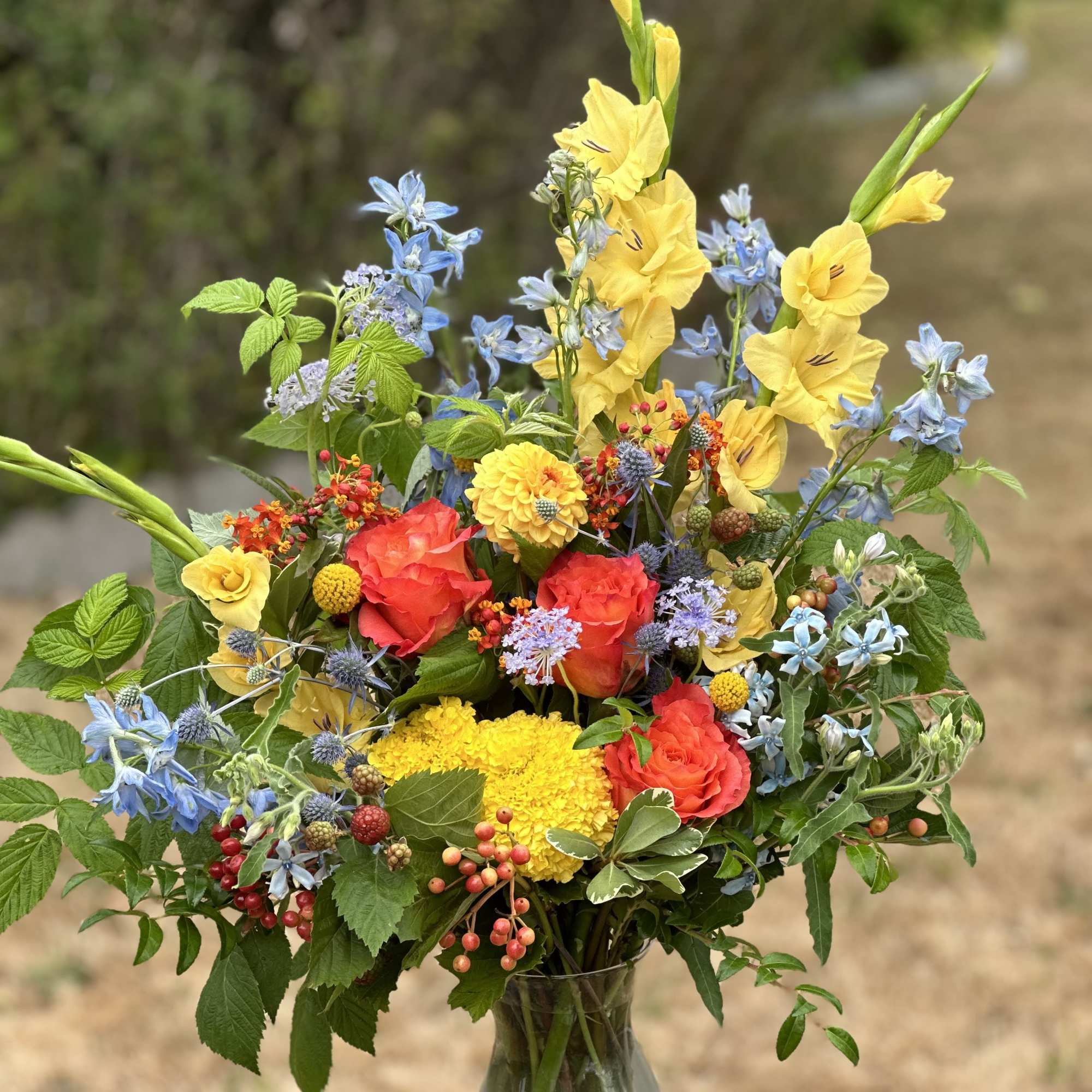 Colorful mixed bouquet in a clear glass vase with yellow, red, and blue flowers