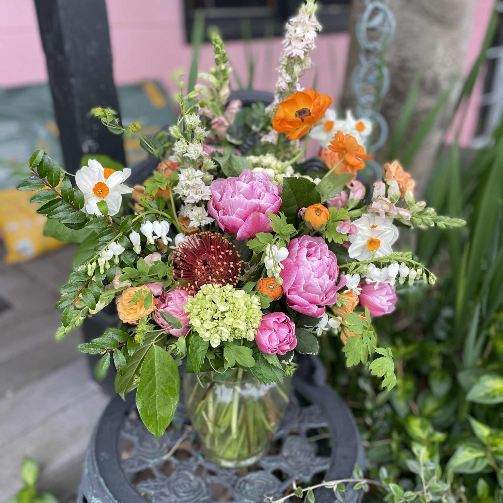 Mixed bouquet of pink, orange, white, and green flowers in a glass vase