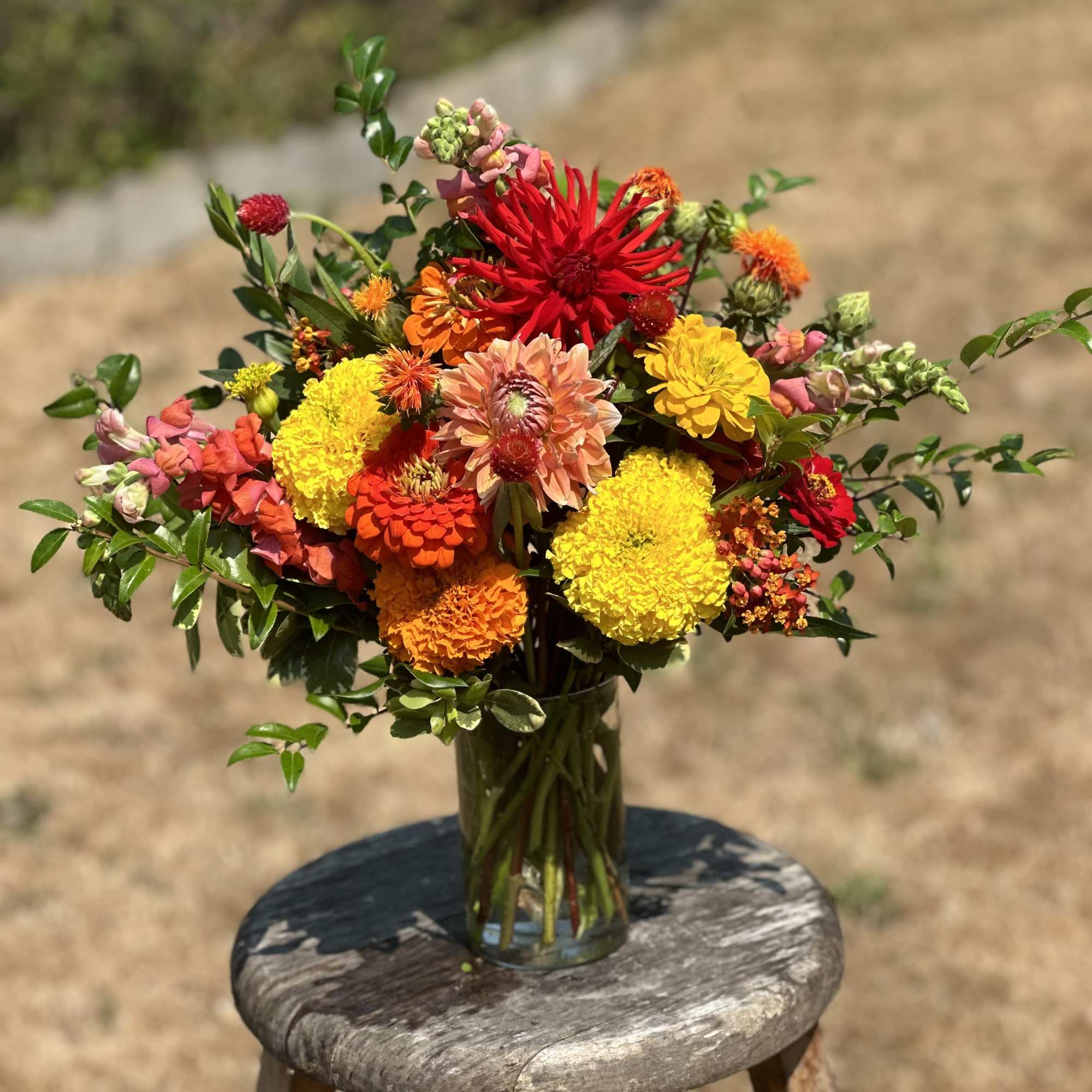 Colorful mixed bouquet in a clear glass vase on a stool