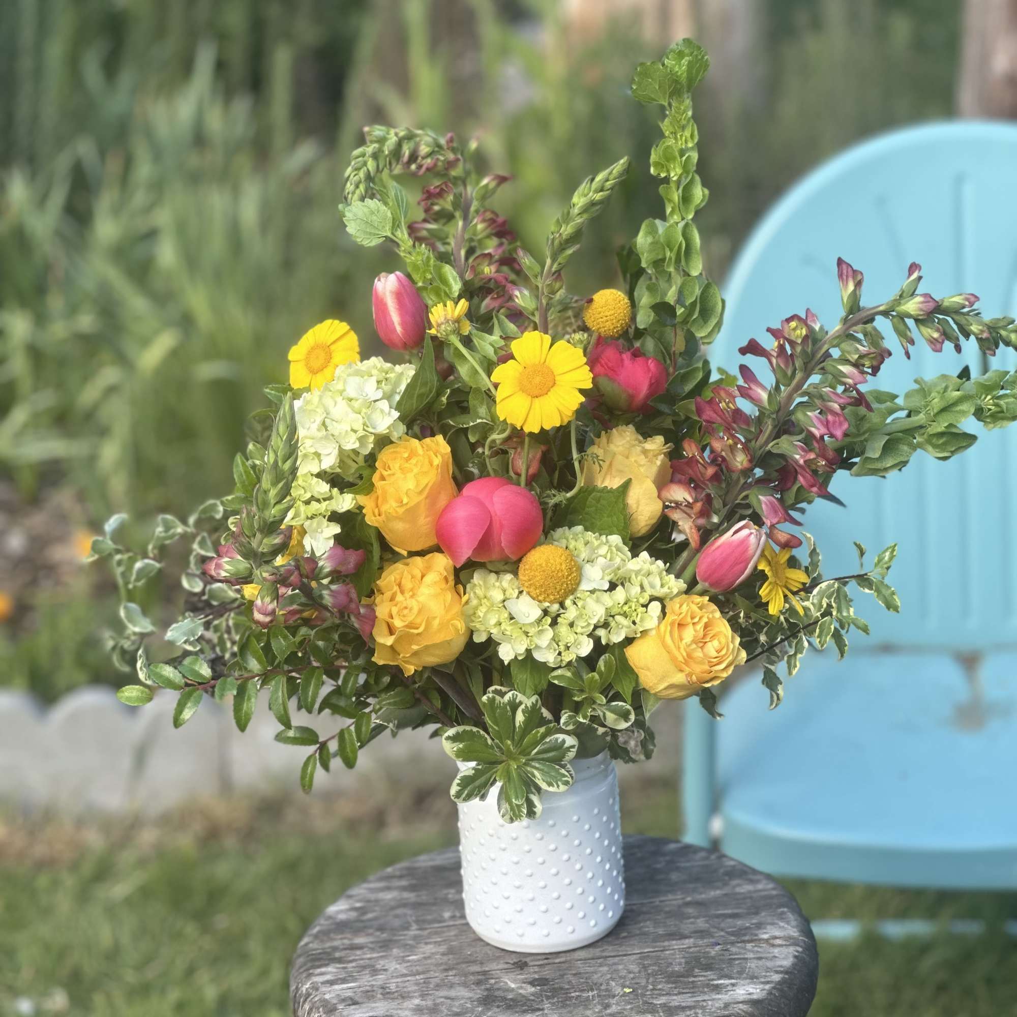 Mixed bouquet of yellow, pink, and white flowers in a white vase