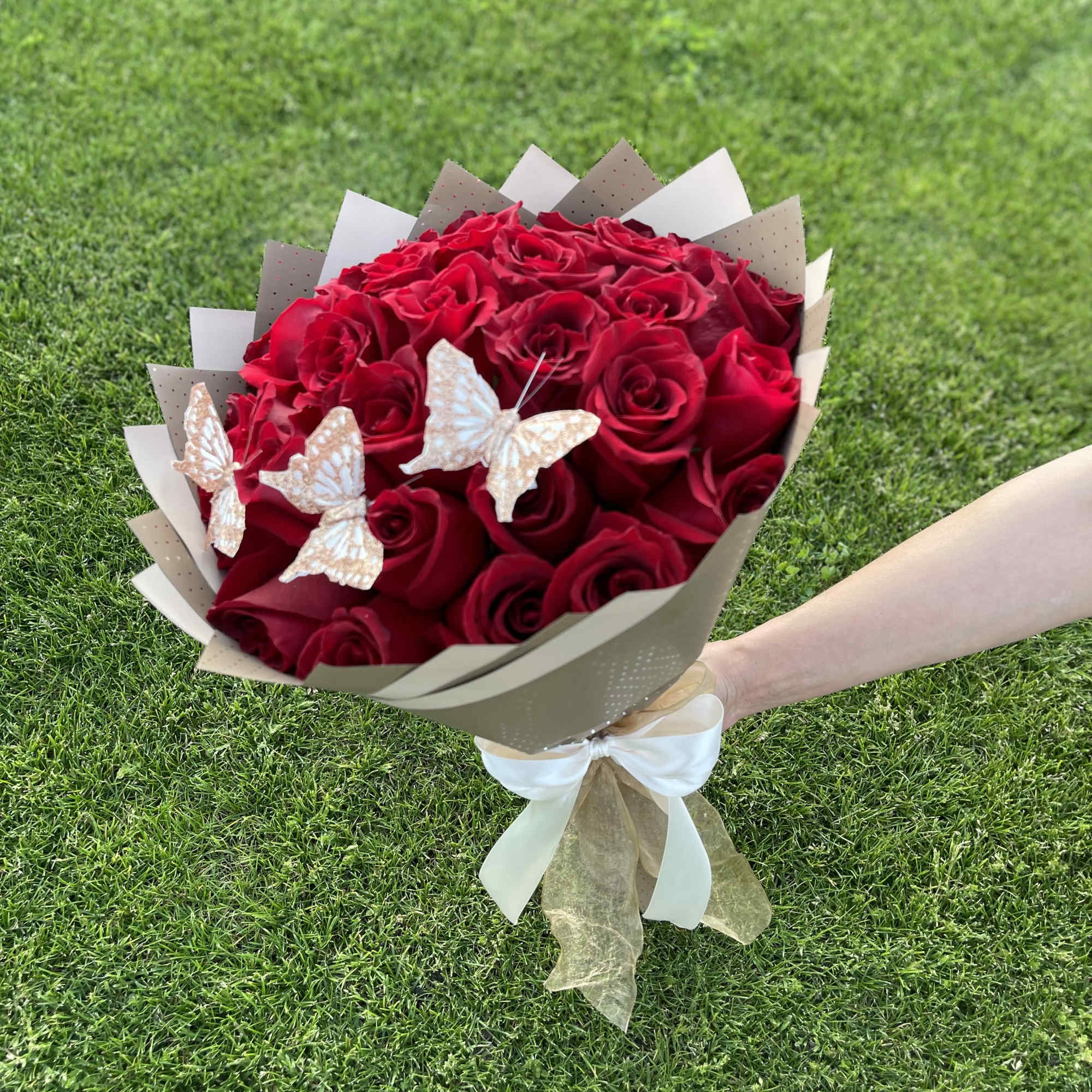 Bouquet of red roses with butterfly decorations and beige wrapping