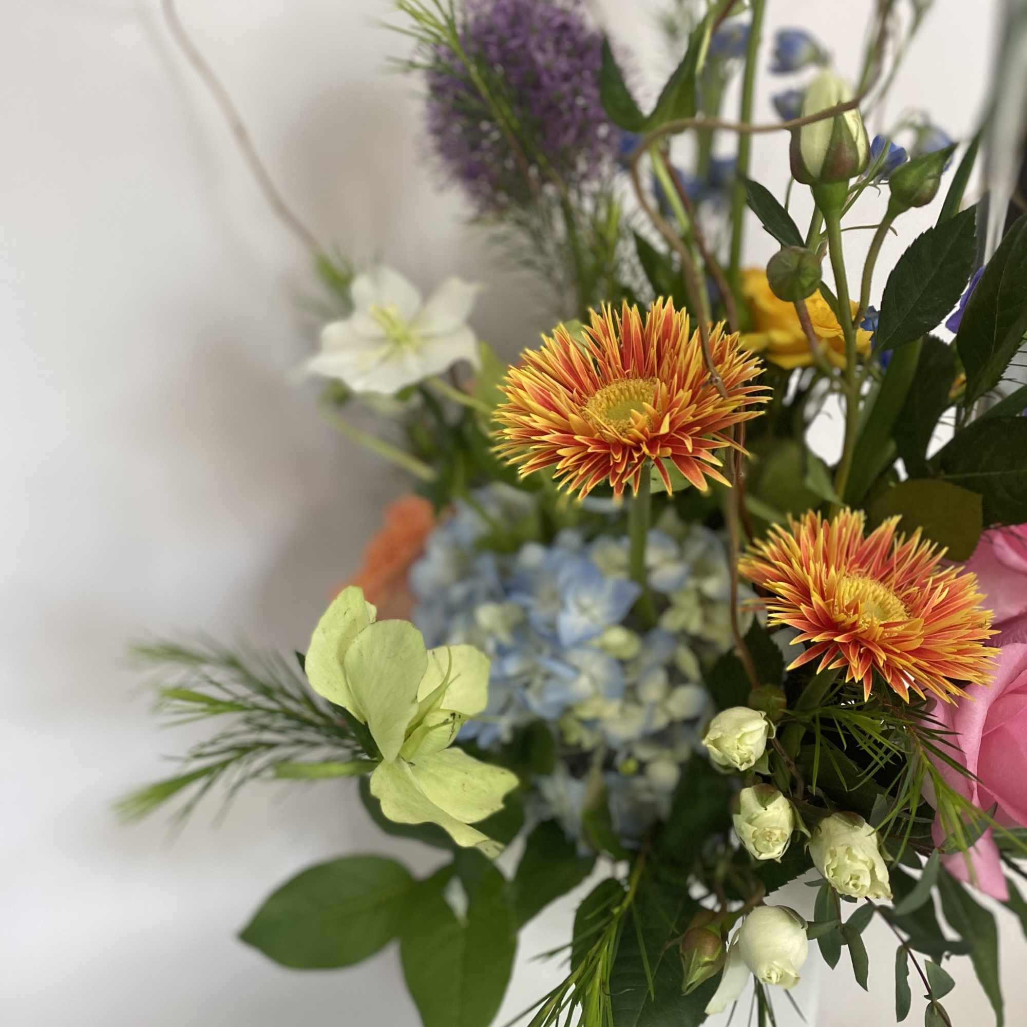 Mixed bouquet with orange daisies, blue hydrangea, and purple blooms