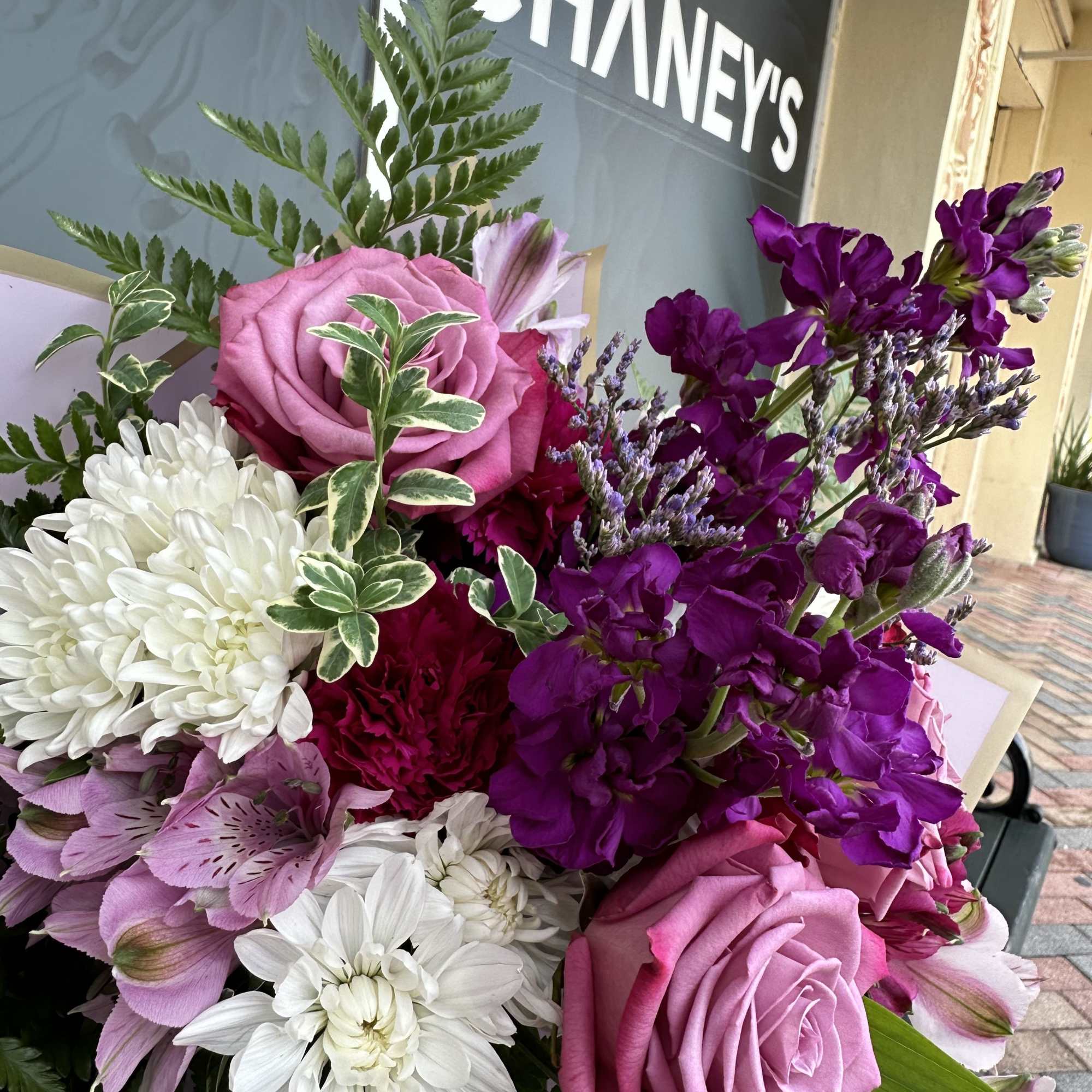 Pink roses and purple flowers arranged with white daisies