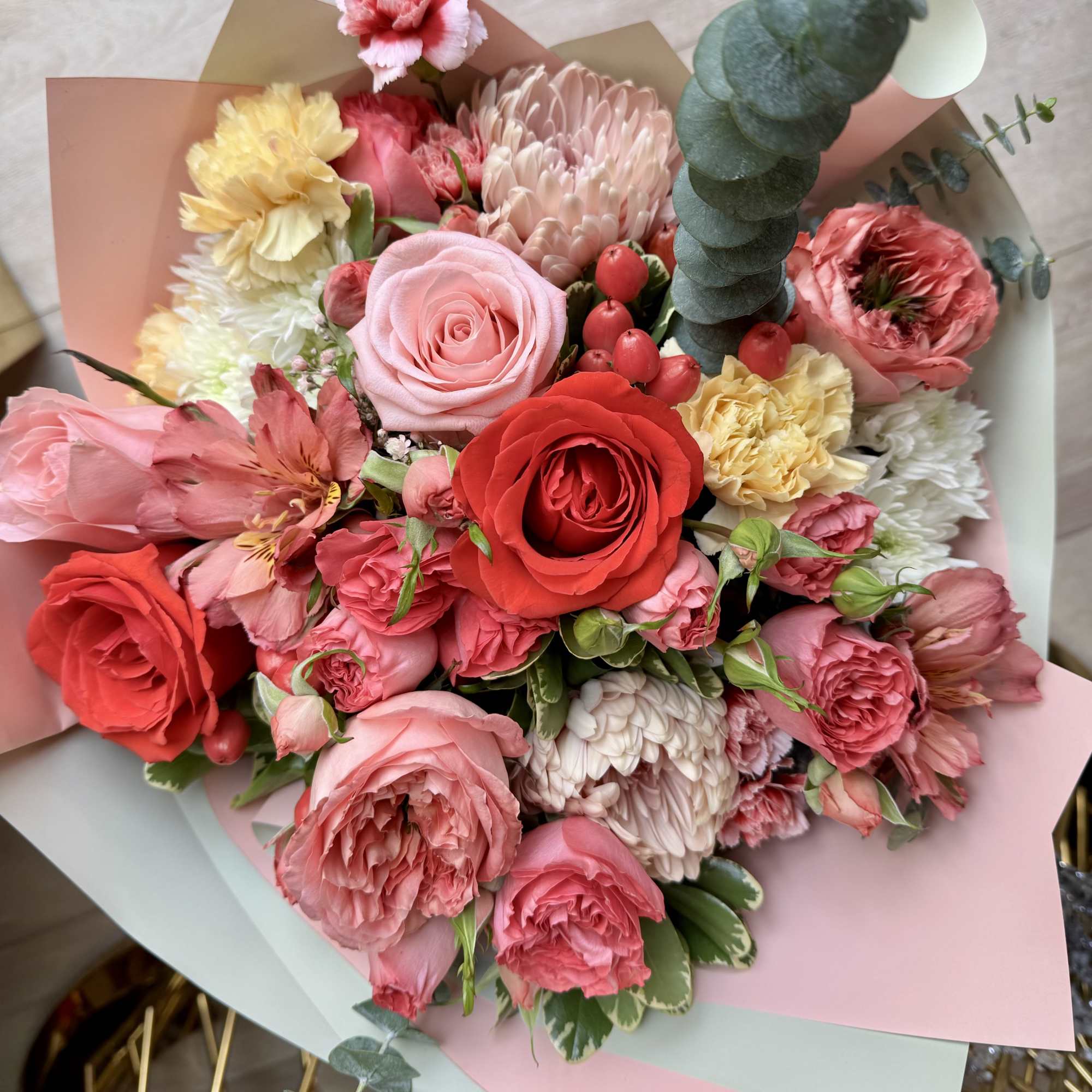 Bouquet of pink and red roses with mixed blooms wrapped in pastel paper
