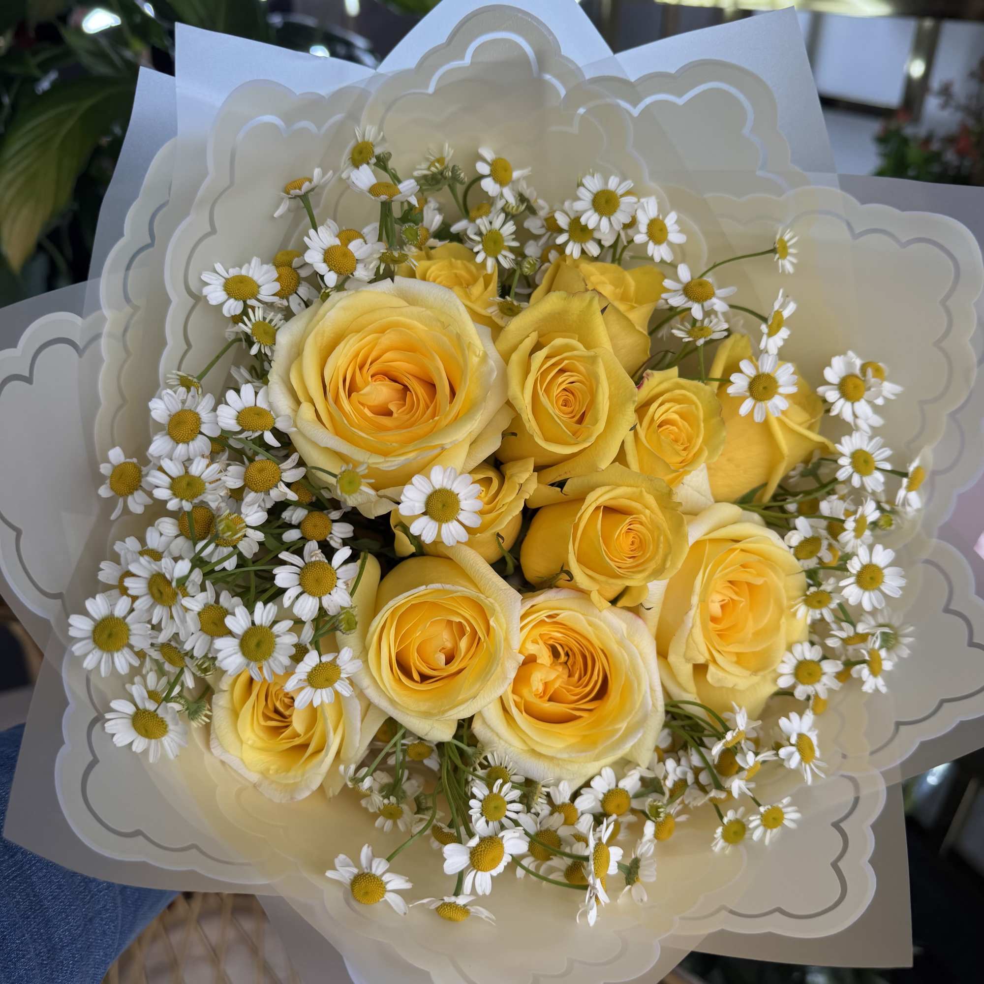 Bouquet of yellow roses and small white daisies wrapped in cream paper