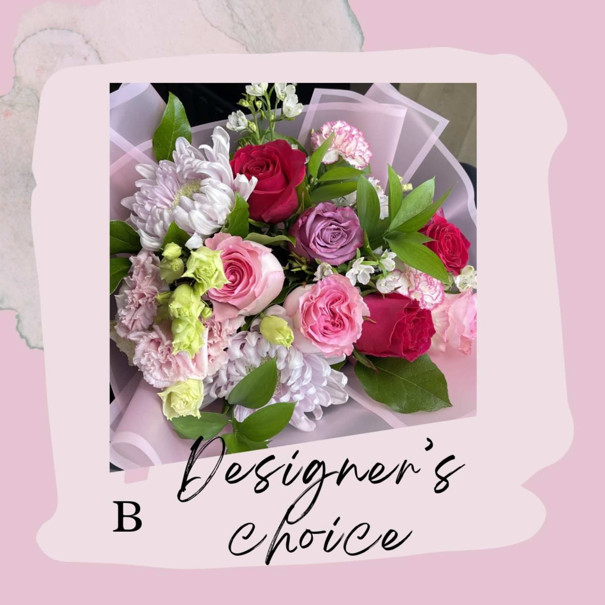 Mixed bouquet of pink, red, and white flowers wrapped in pale pink paper
