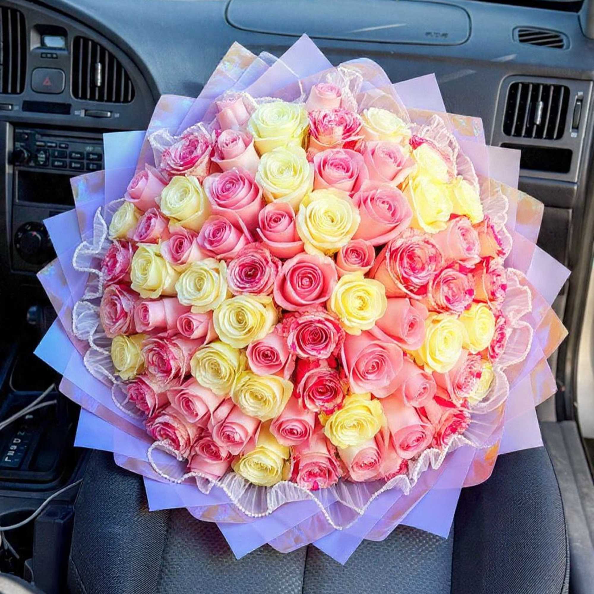 A lush, tightly packed hand-tied bouquet of roses in soft pinks, pale