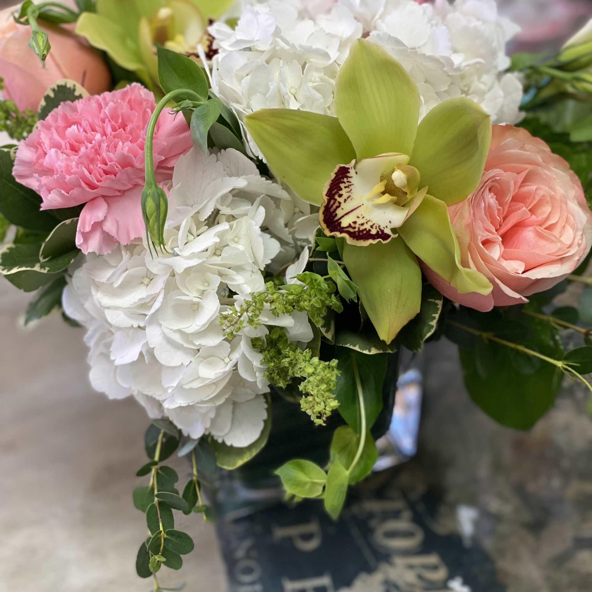 Hydrangeas, carnations, and roses in a cube with a cheerful garden feel
