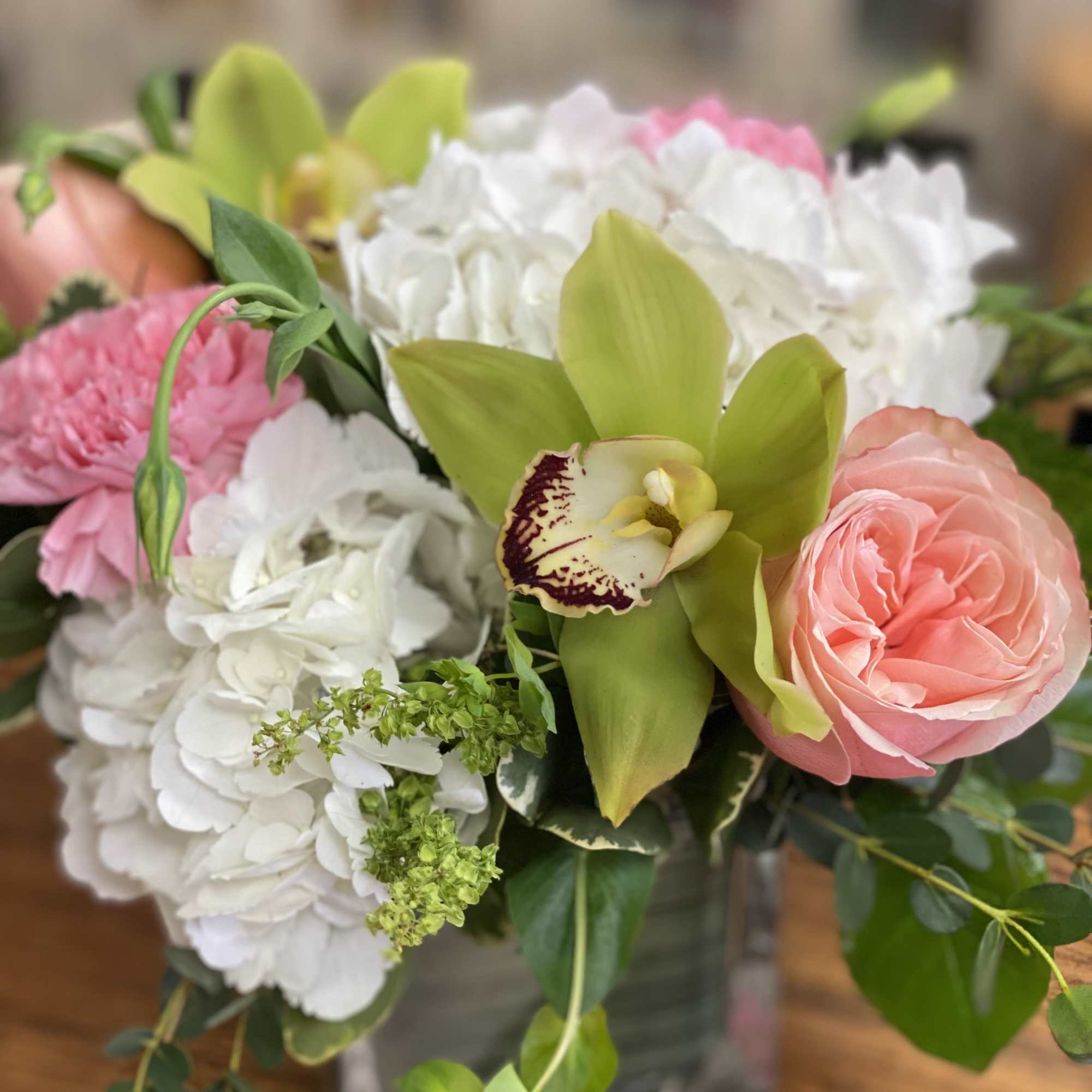 Hydrangeas, carnations, and roses in a cube with a cheerful garden feel