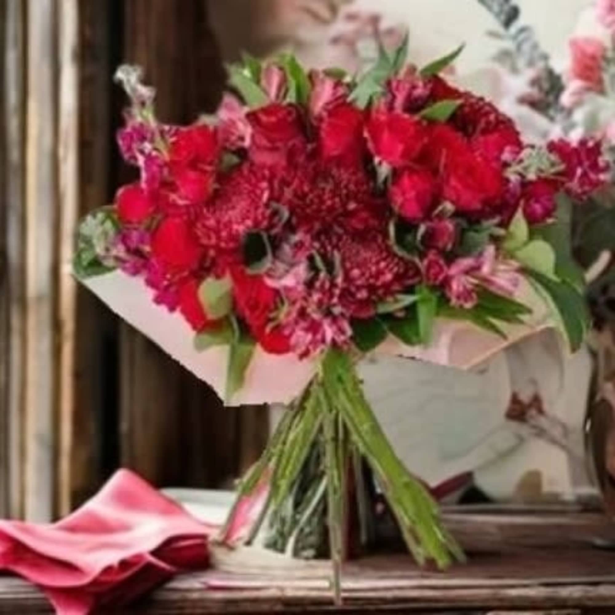 Bouquet of red and pink flowers wrapped in pale paper