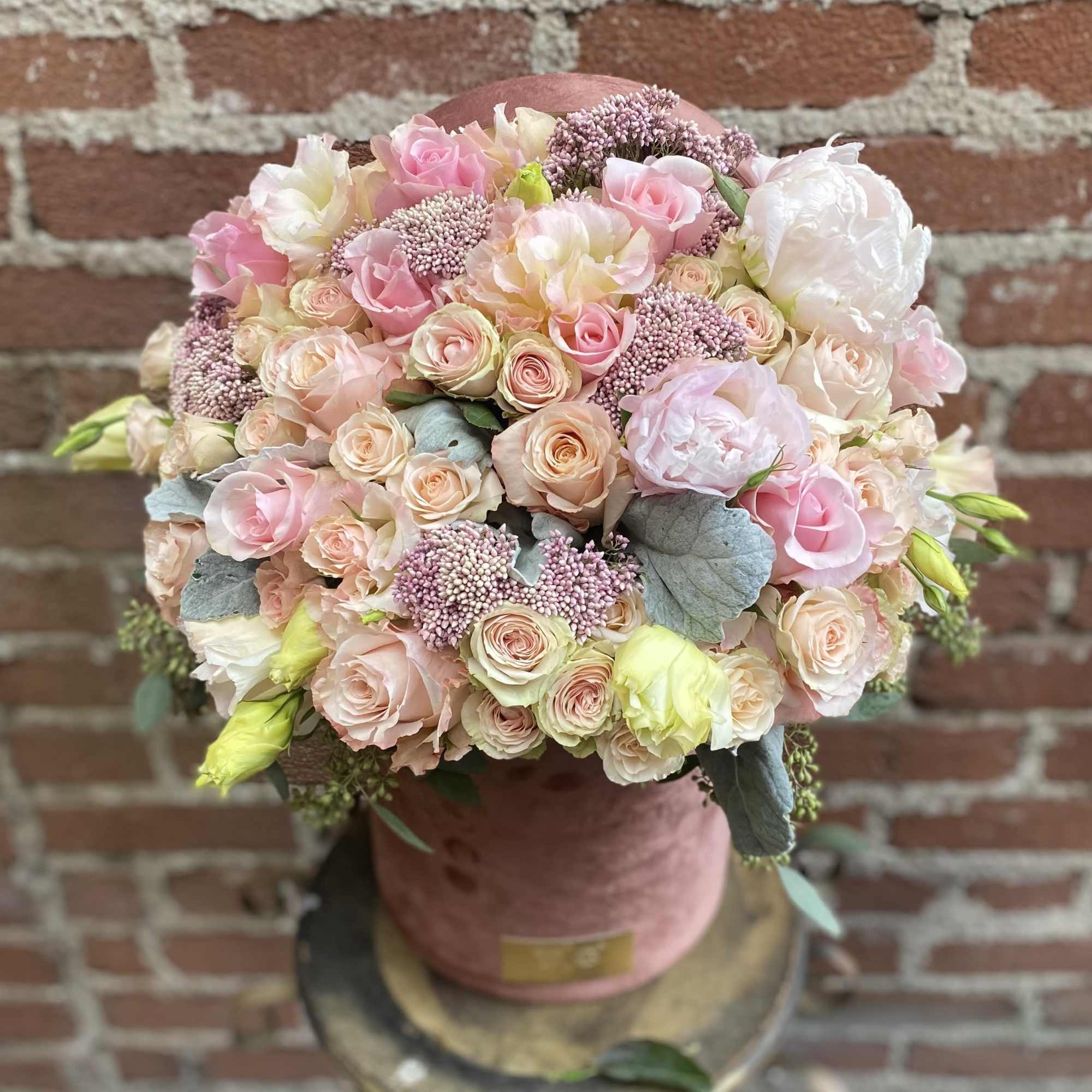 Round bouquet of blush pink and cream roses in a pink hatbox