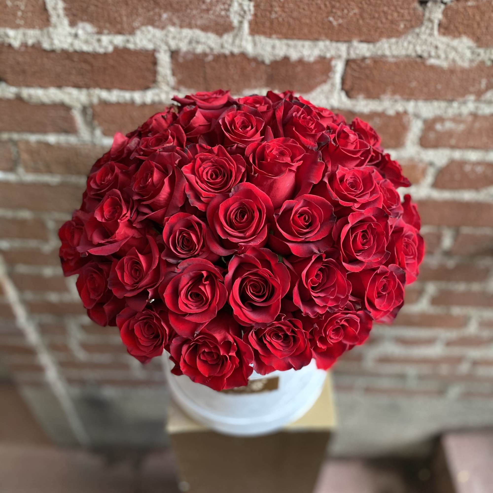 Round bouquet of red roses in a white container