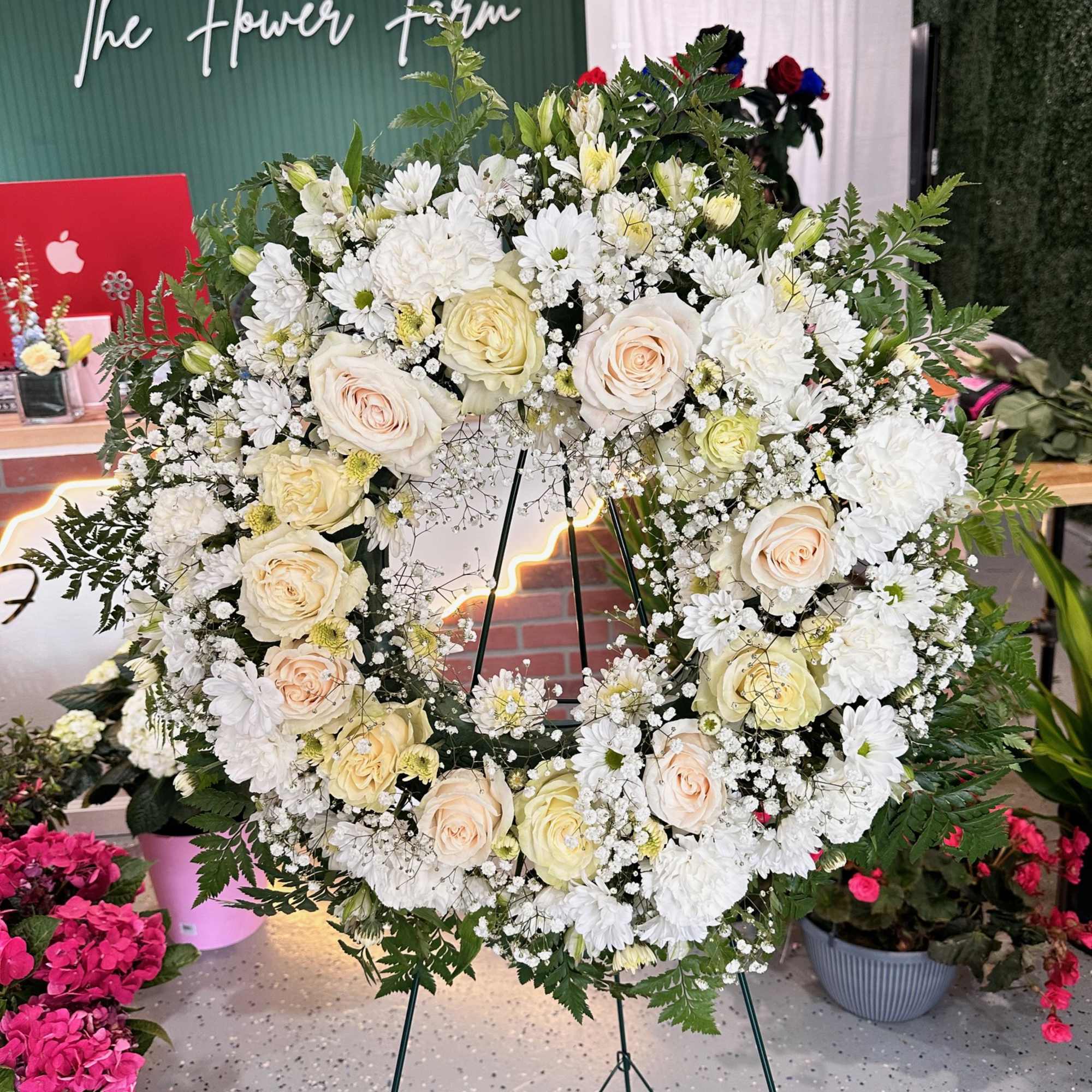 Large white floral wreath on a stand with cream roses and daisies