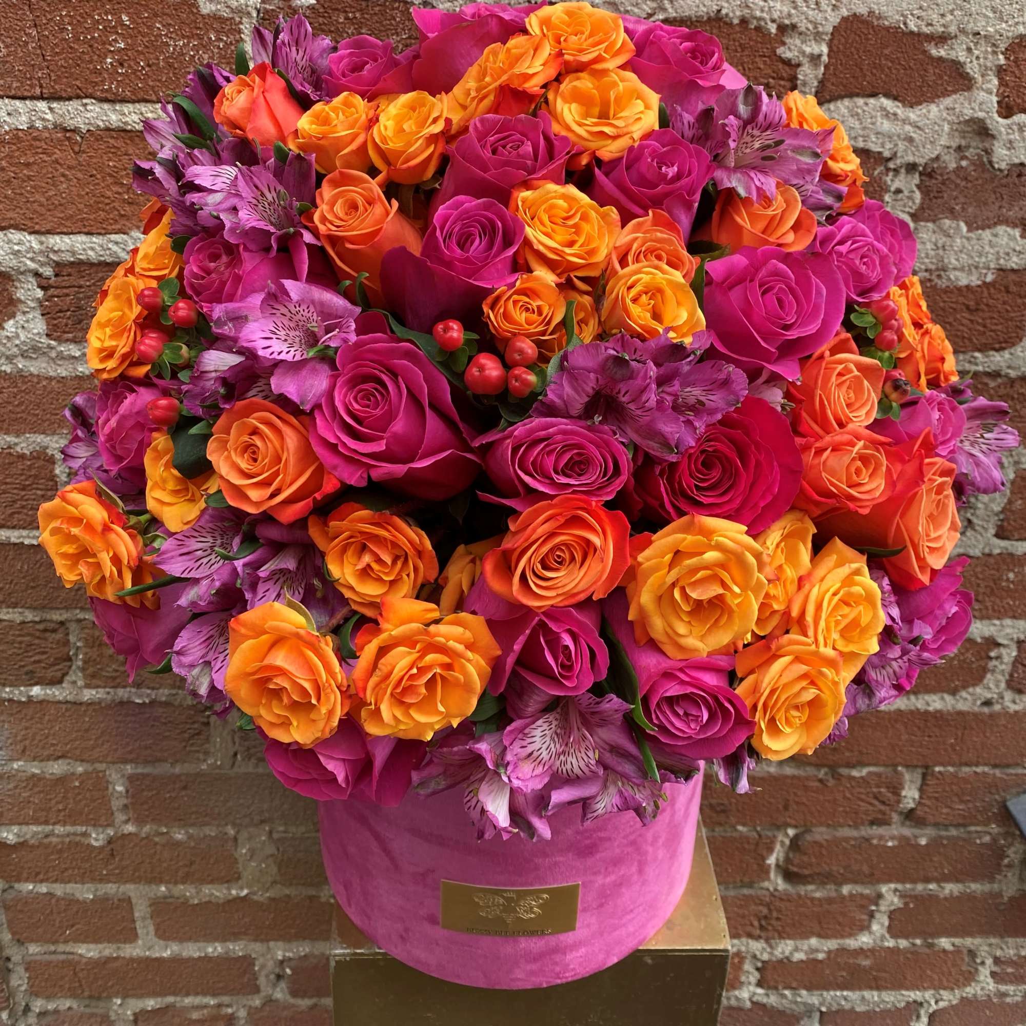 Bright bouquet of pink, orange, and purple roses in a pink hat box