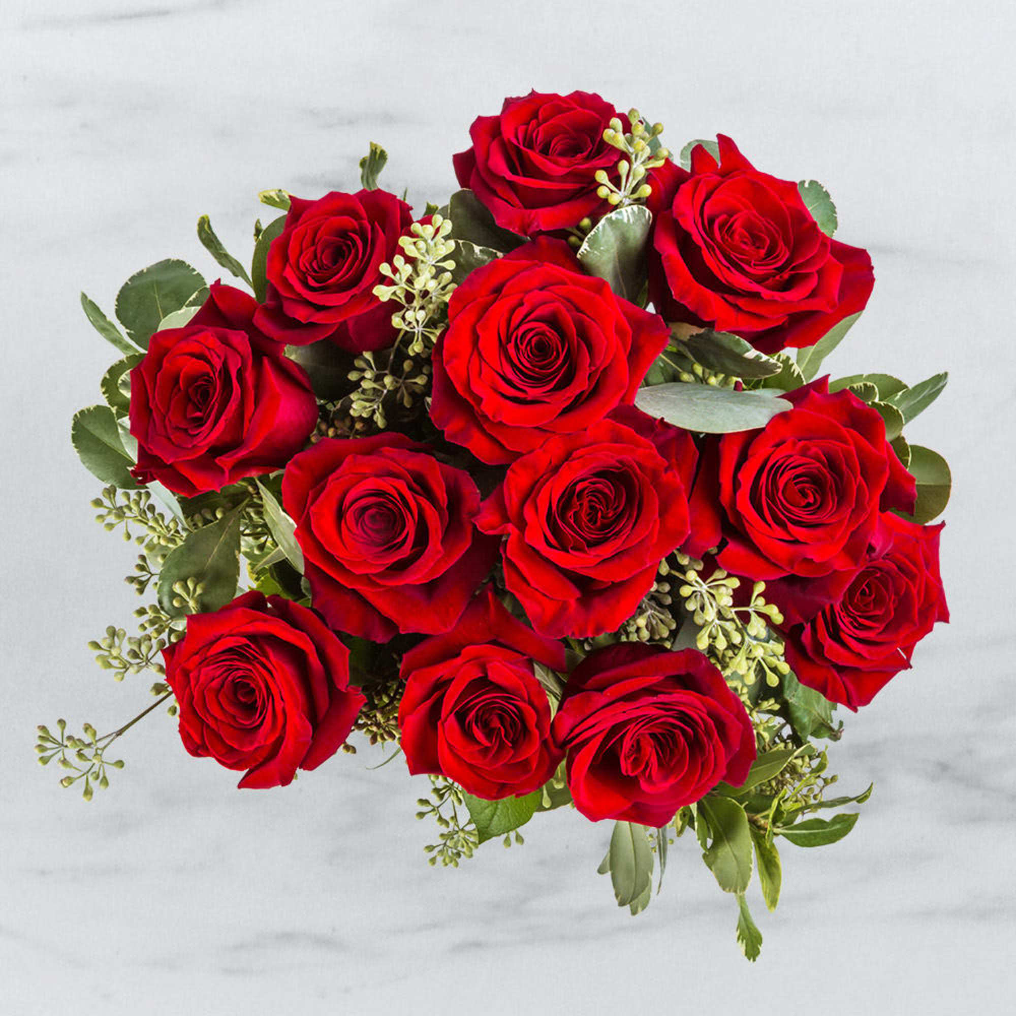 Bouquet of red roses with greenery on a light background
