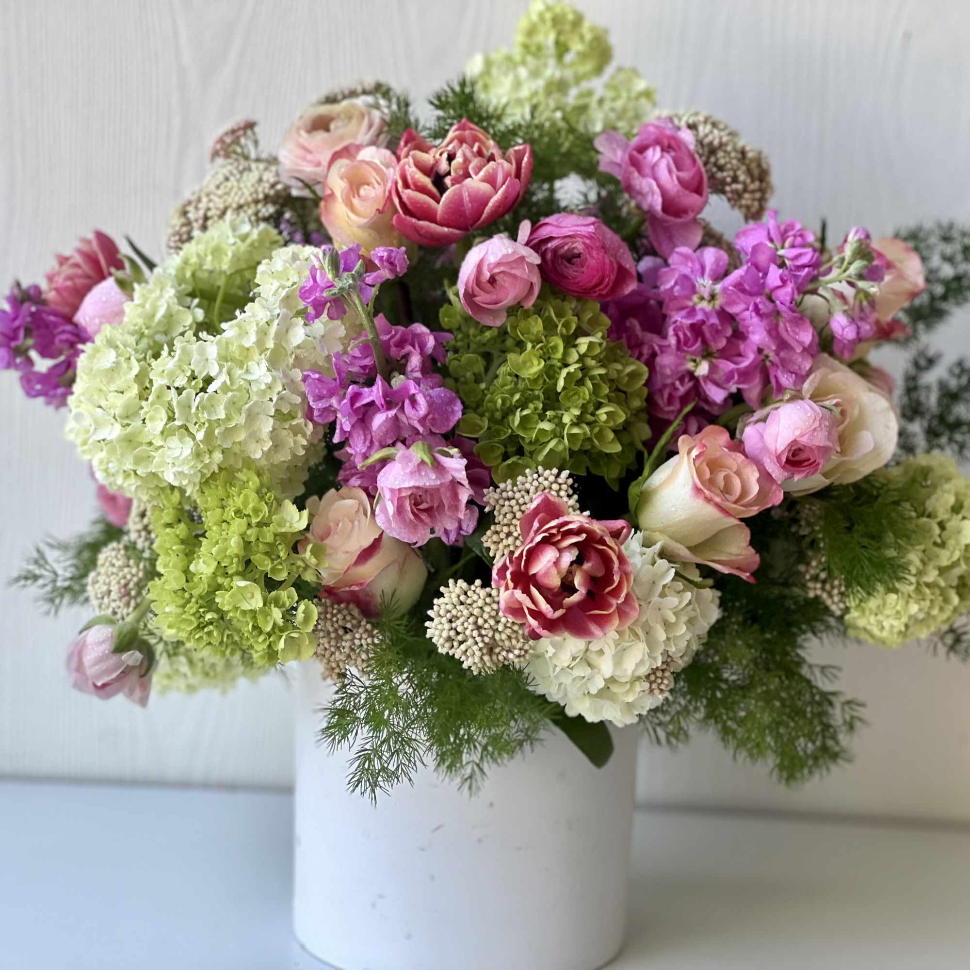 Mixed pink and green floral arrangement in a white vase