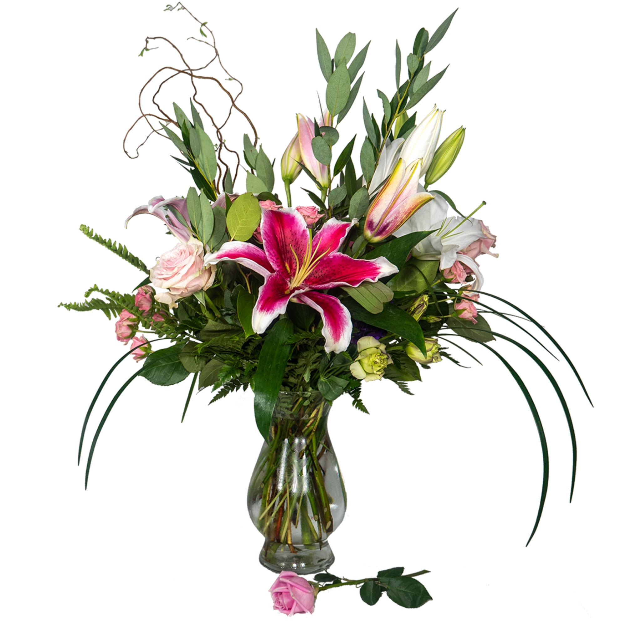 Tall arrangement of pink lilies and roses in a clear glass vase with a single pink rose at the base