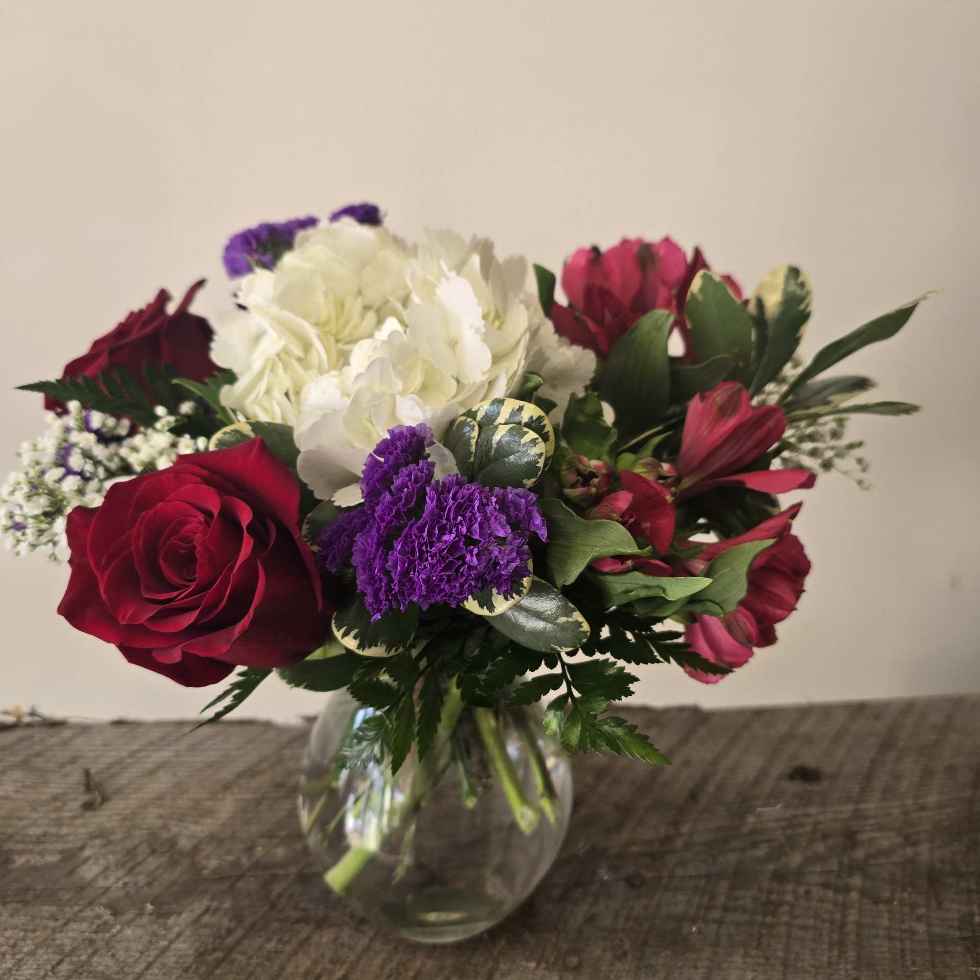 Bouquet of red, white, and purple flowers in a round glass vase