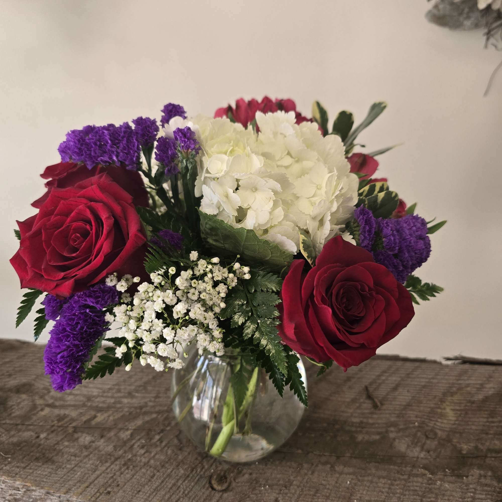 Red roses and white hydrangea in a clear glass vase