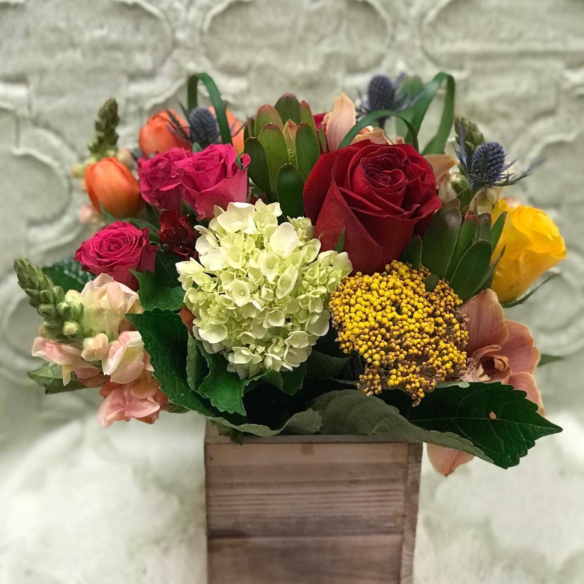 Mixed bouquet in a wooden box with red, pink, white, and yellow blooms