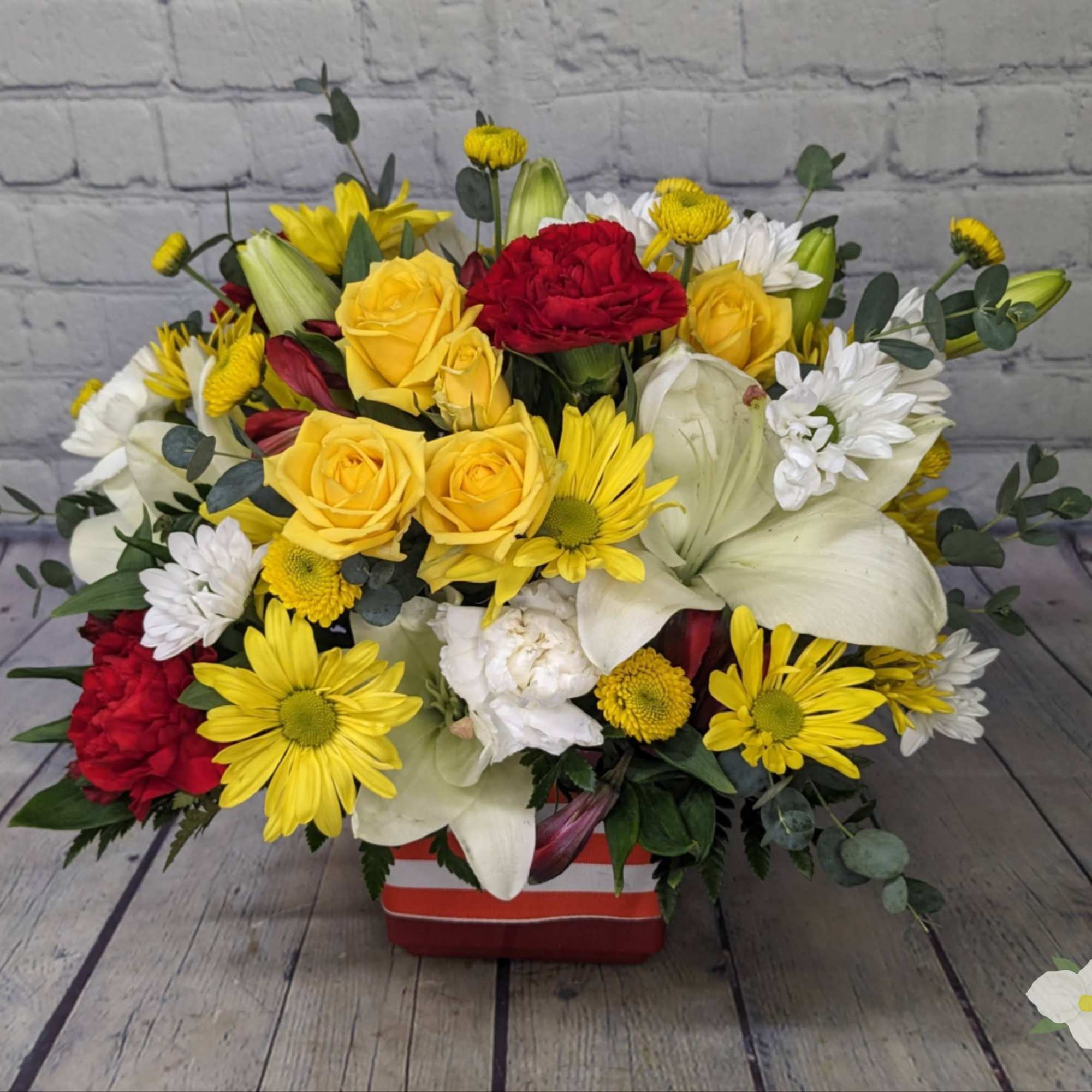 Mixed bouquet of yellow and red flowers in a red striped container