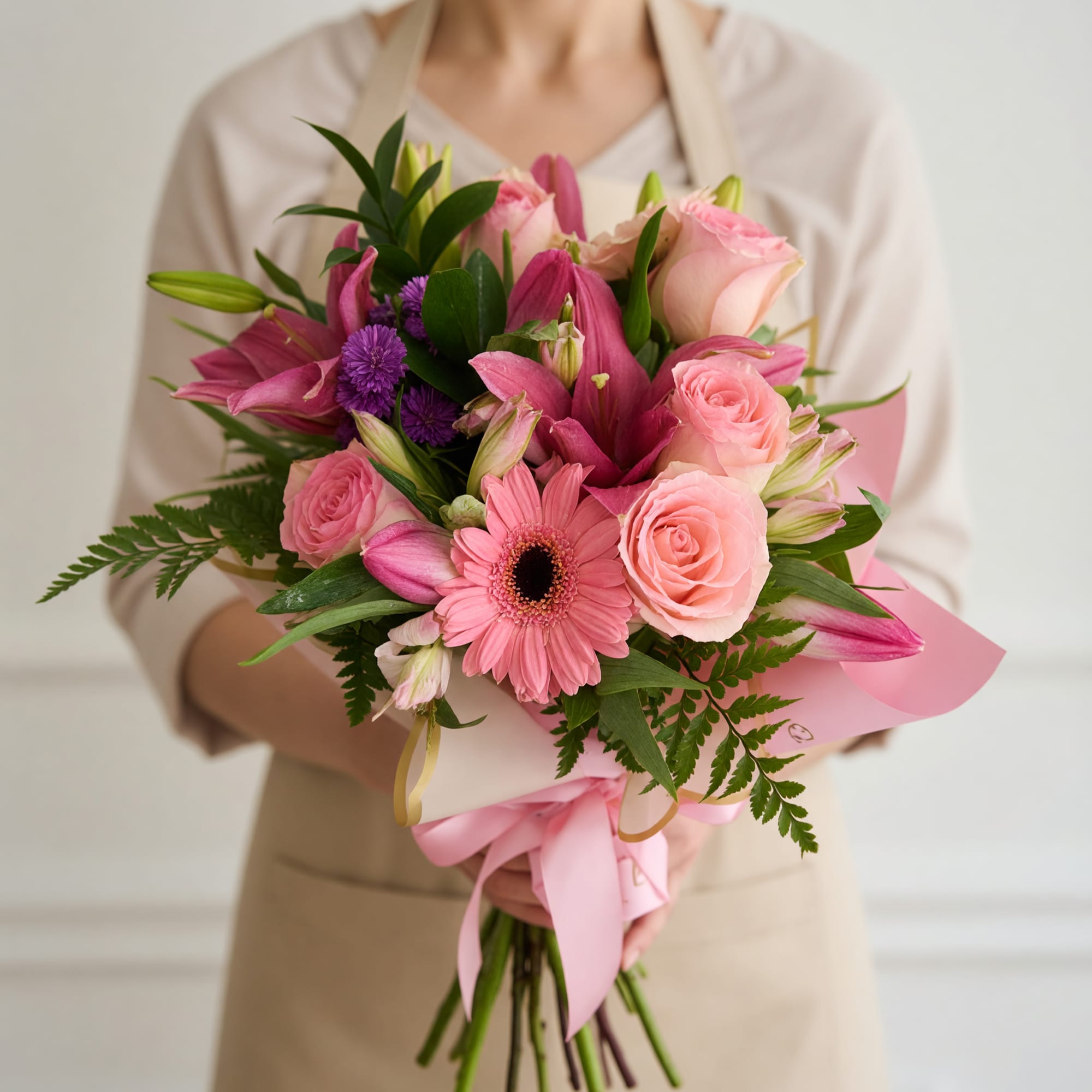 Soft pink roses, a single pink gerbera daisy and bold magenta lilies