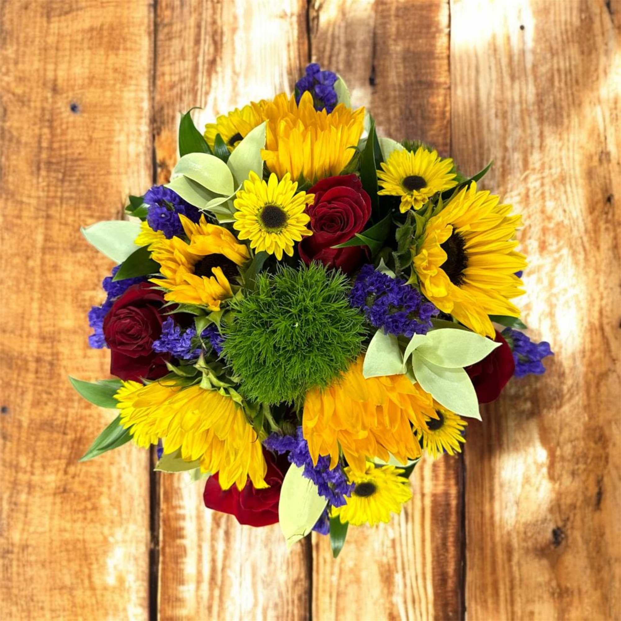 Bouquet of yellow sunflowers and red roses with purple accents