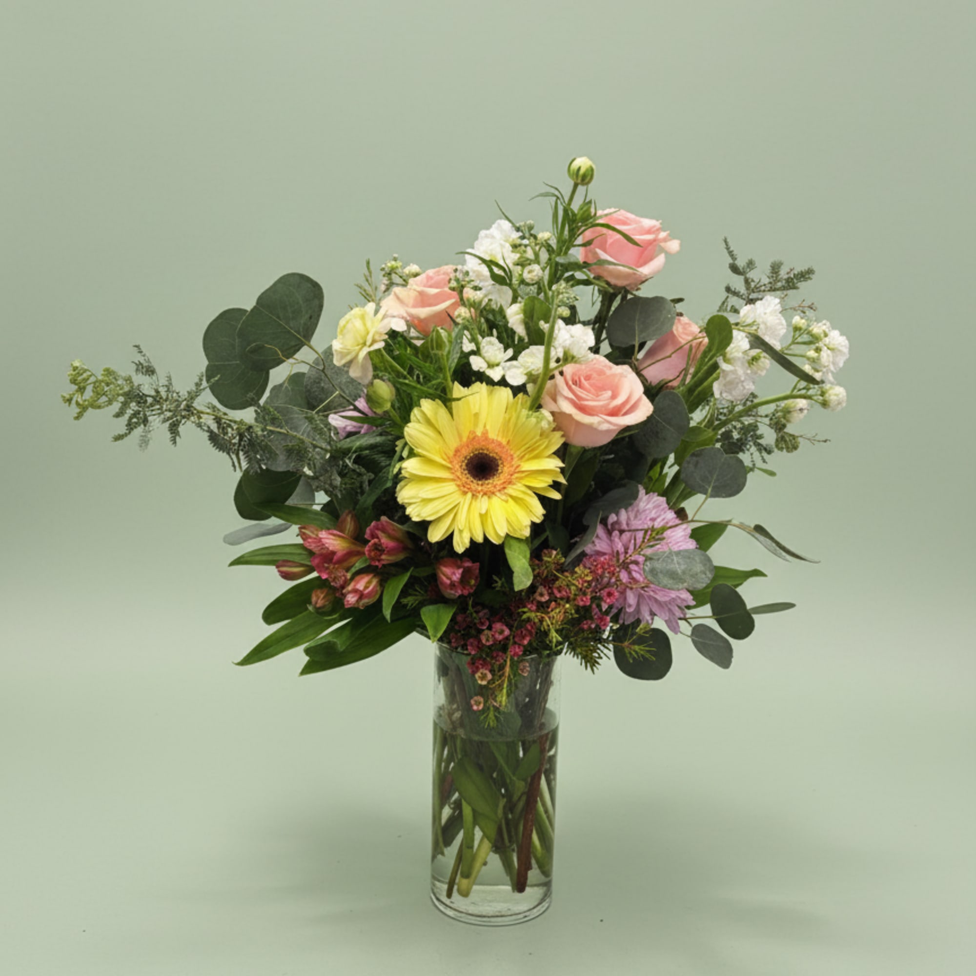 A single bright yellow gerbera daisy anchors this airy garden-style flower arrangement