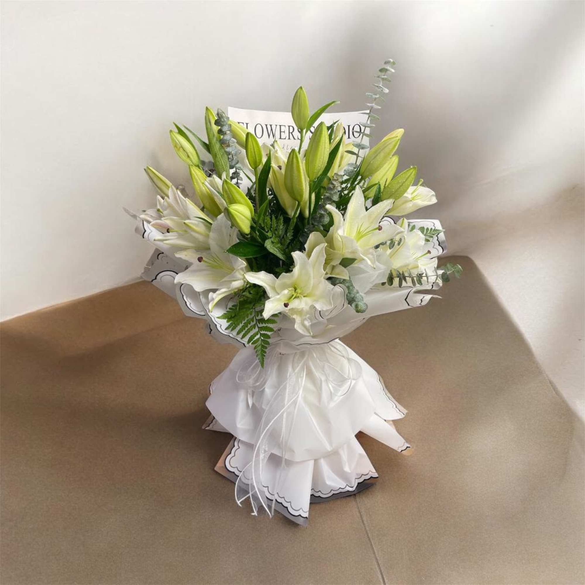 White lily bouquet wrapped in white paper with a ribbon