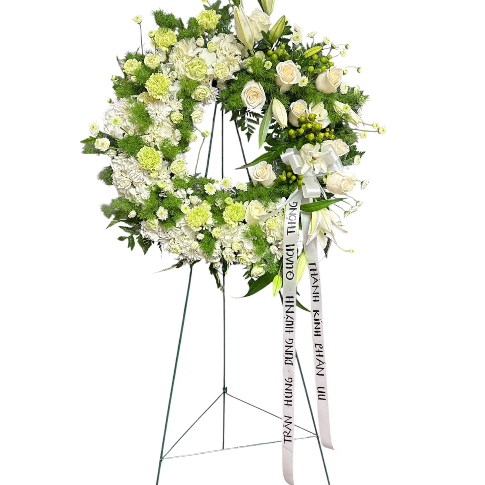 White and green funeral wreath on a stand with ribbon