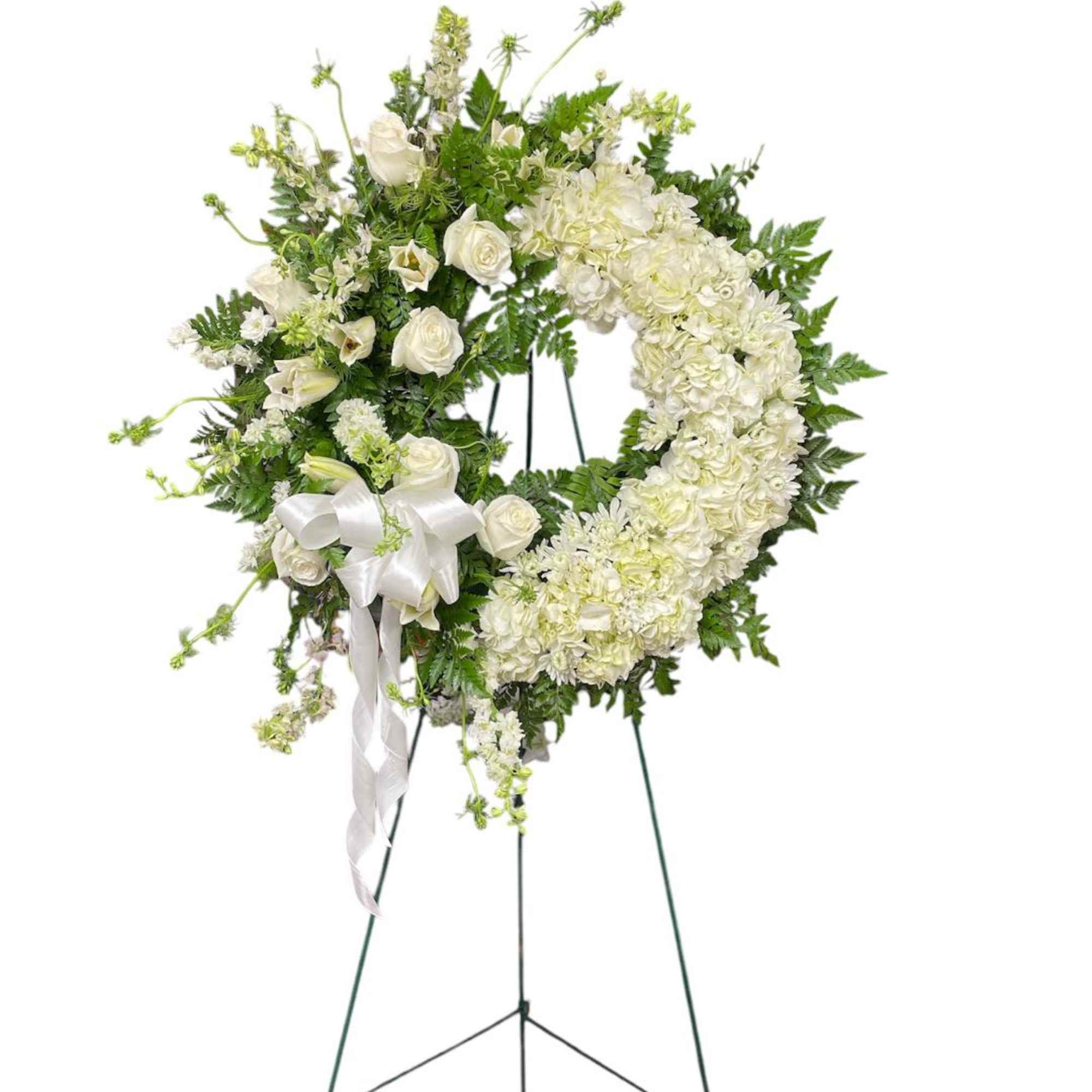 White floral wreath on a standing easel with a ribbon bow