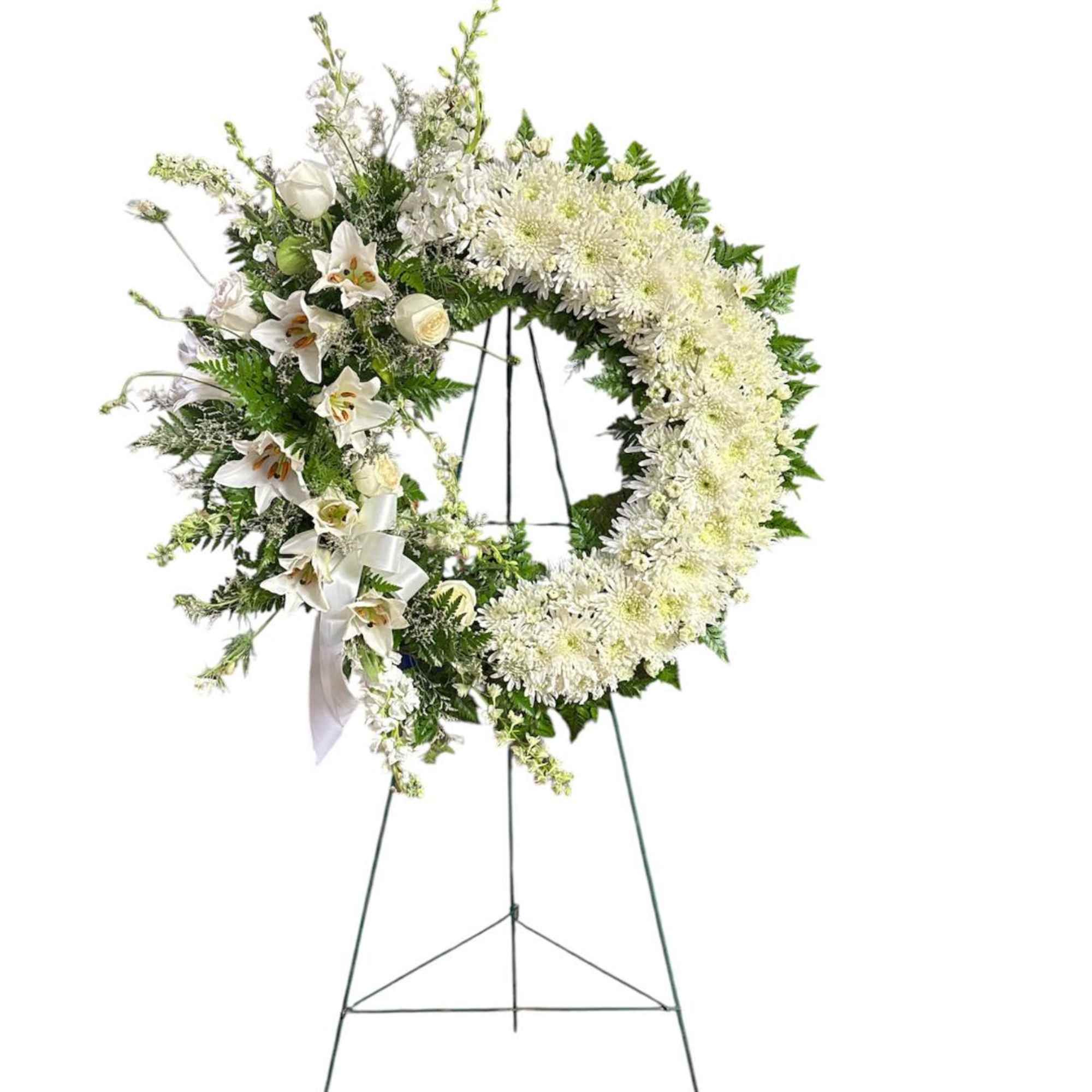 White floral standing wreath on an easel with a ribbon accent