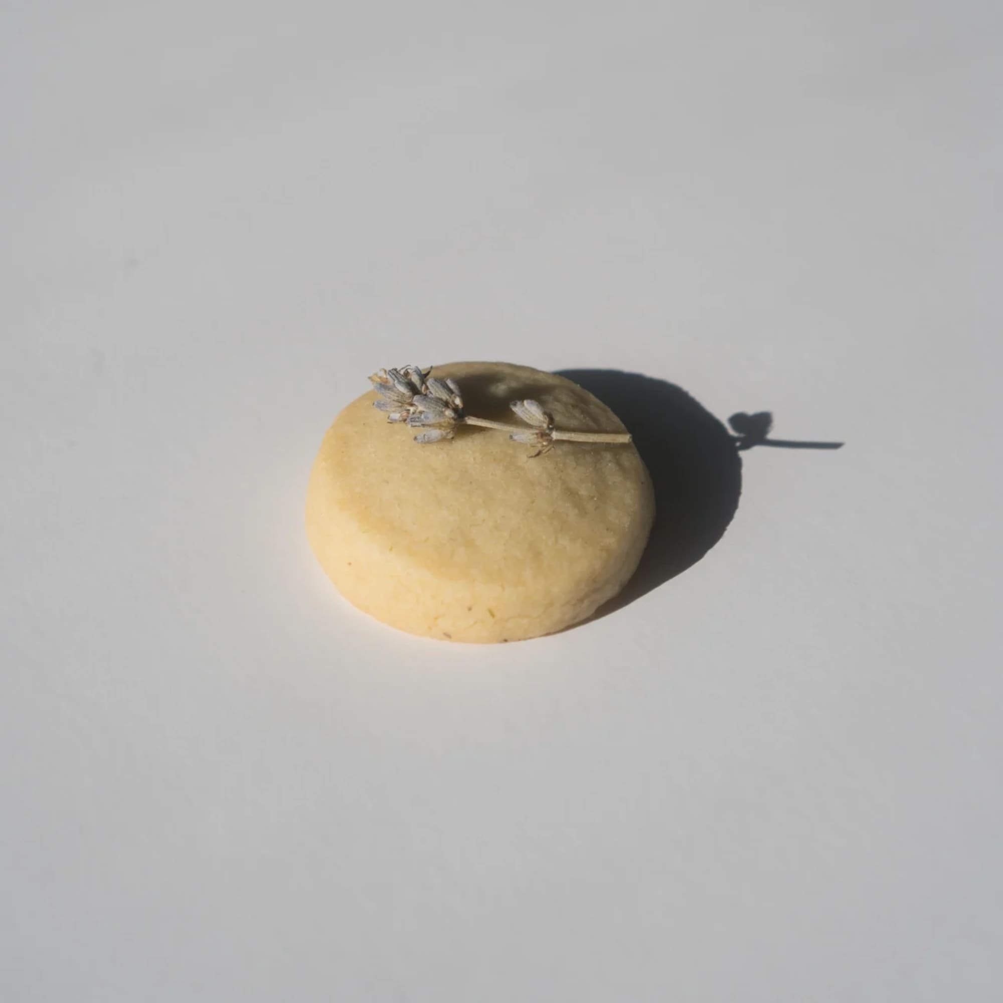 Round yellow pastry with a small dried flower sprig on top