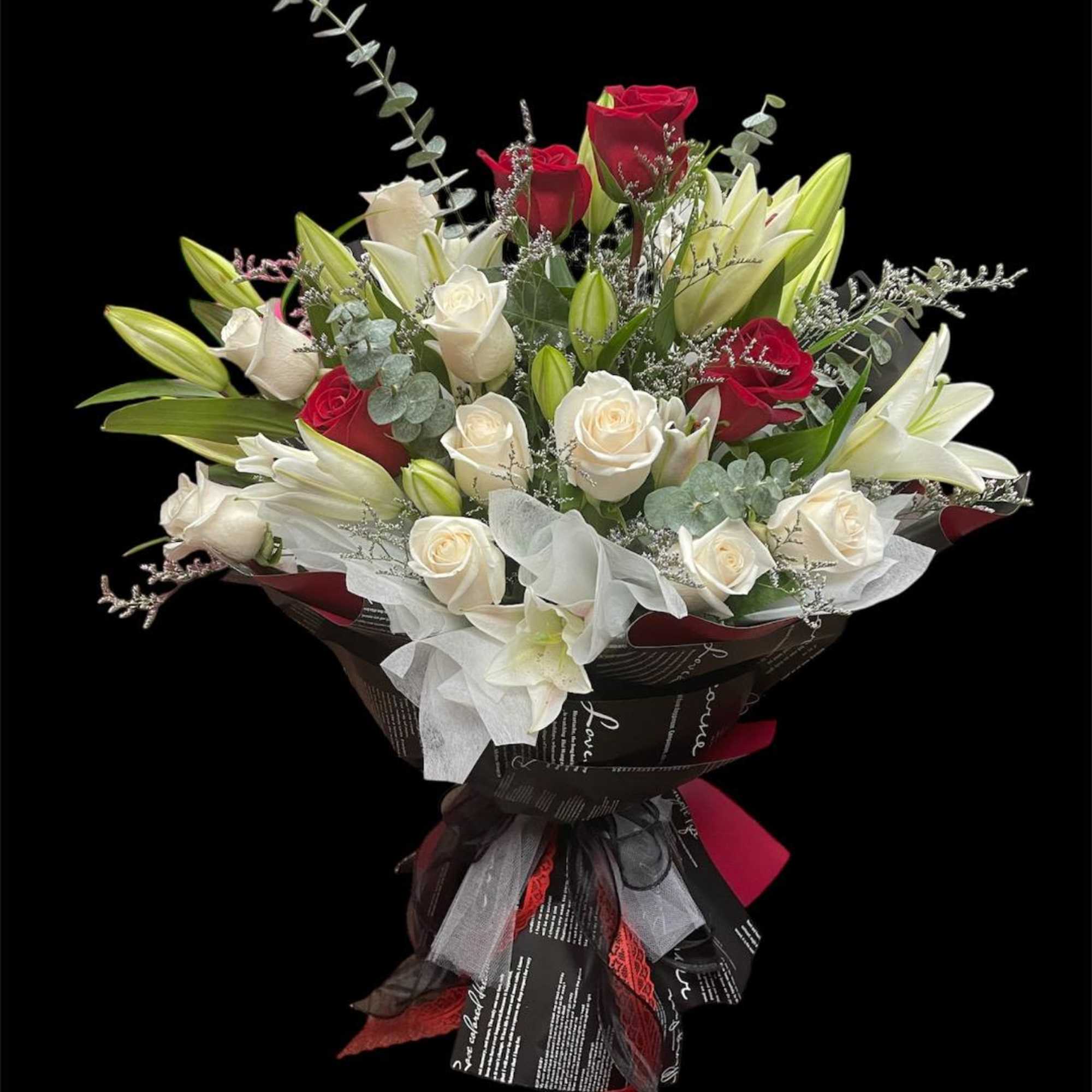 Bouquet of red and white roses with white lilies wrapped in dark paper