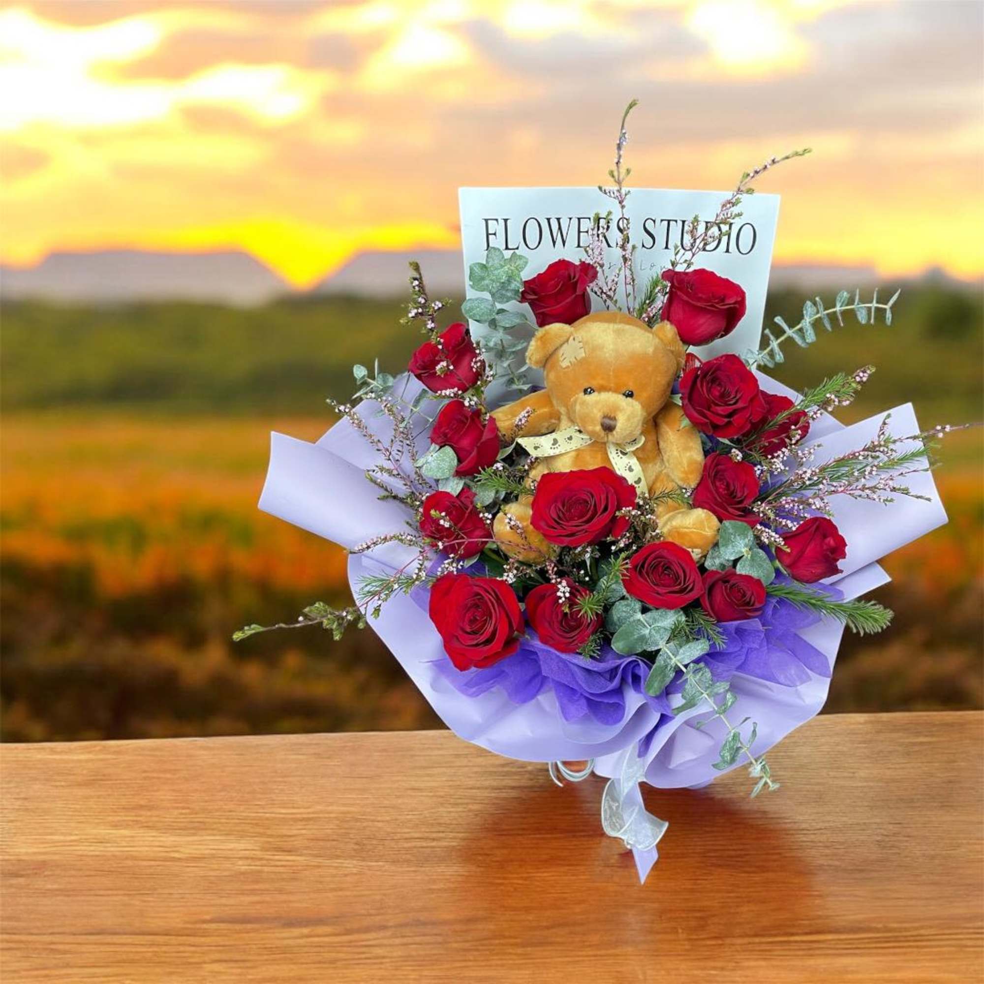Bouquet of red roses with a teddy bear and purple wrapping