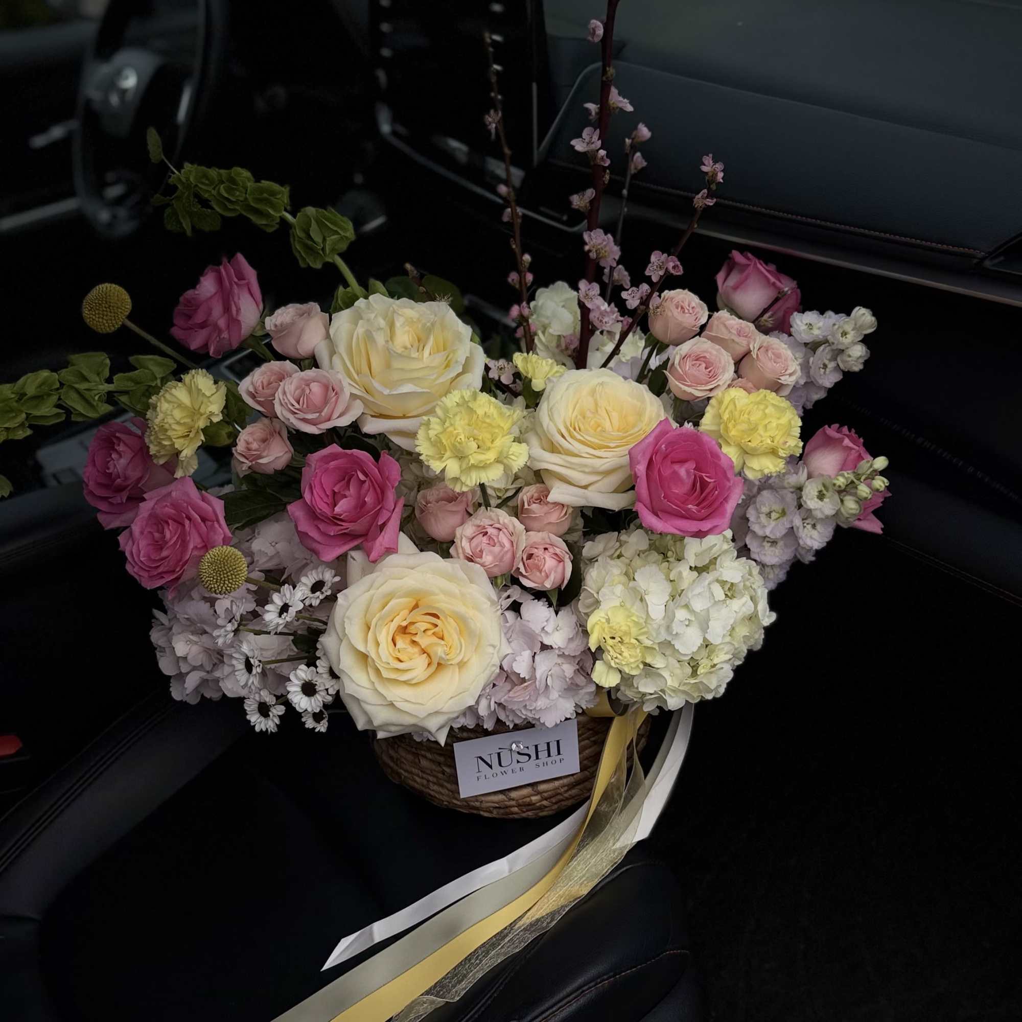 A bright seasonal basket featuring a mix of yellow, pink, white, green
