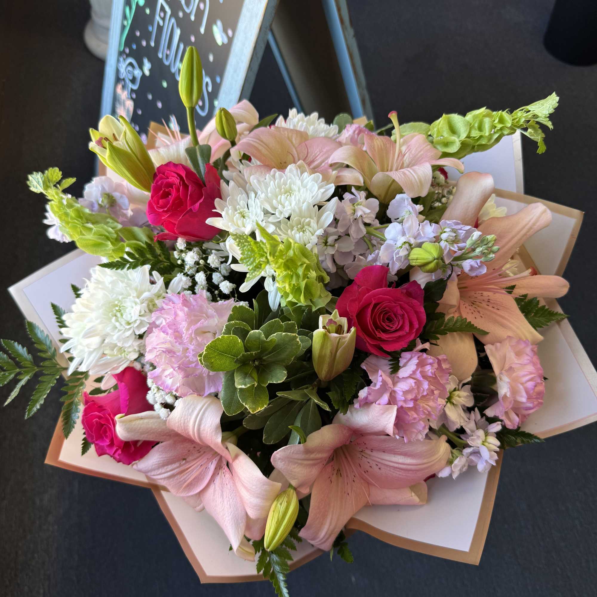 Pink and white lilies, hot-pink roses, chrysanthemums and carnations with green accents