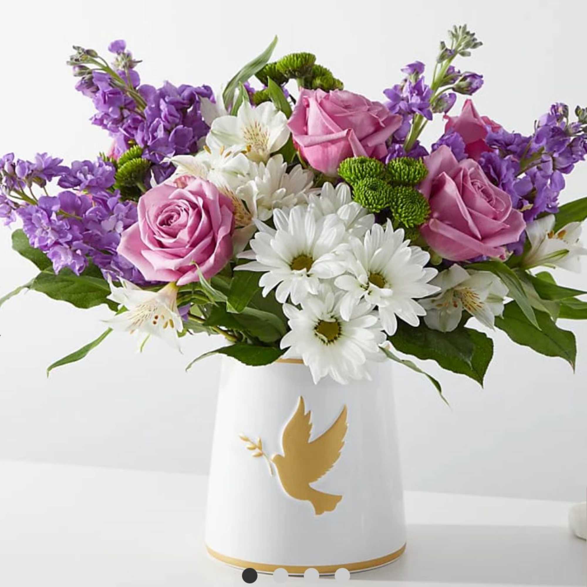 Bouquet of pink roses, white daisies, and purple flowers in a white vase