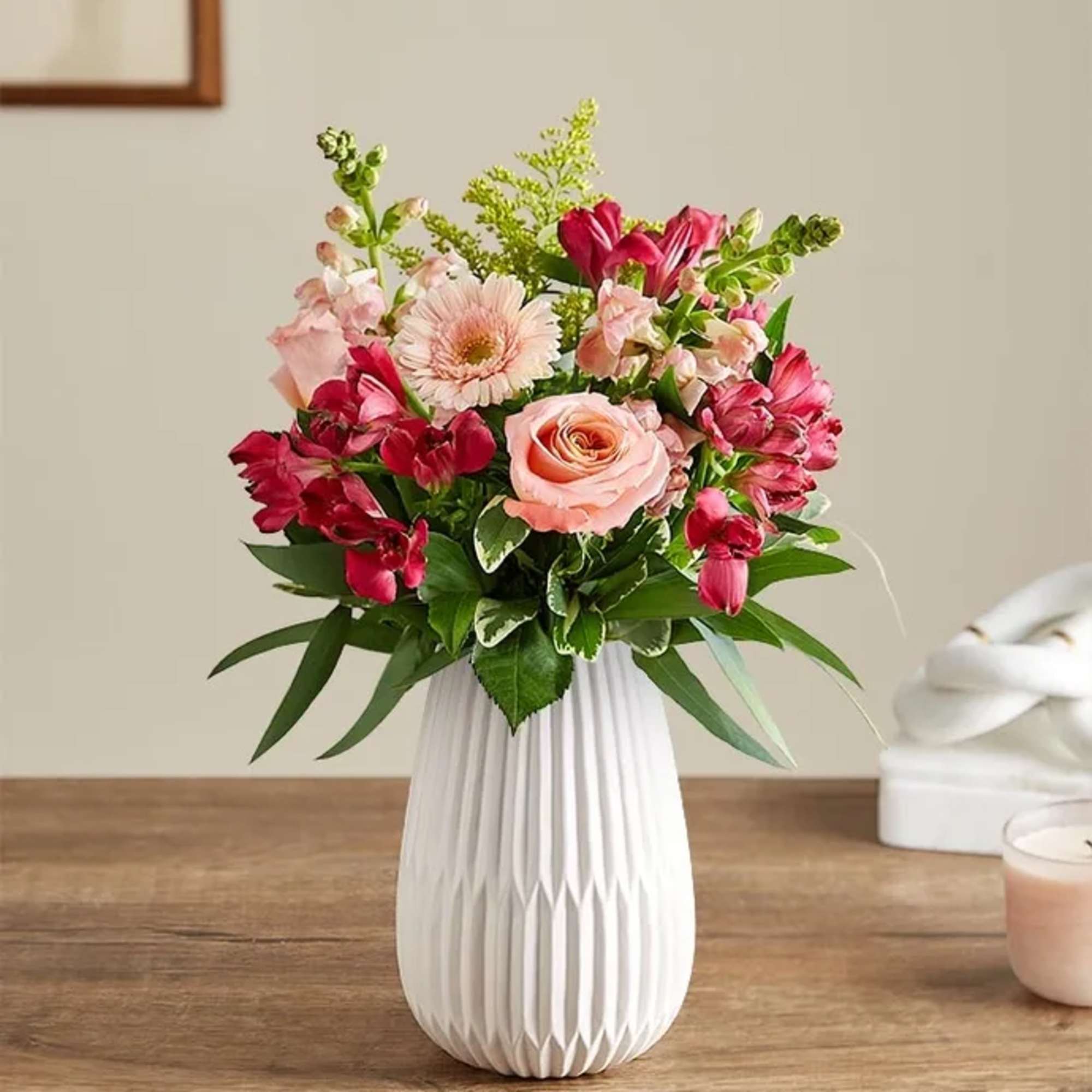Pink and red mixed flower arrangement in a white vase