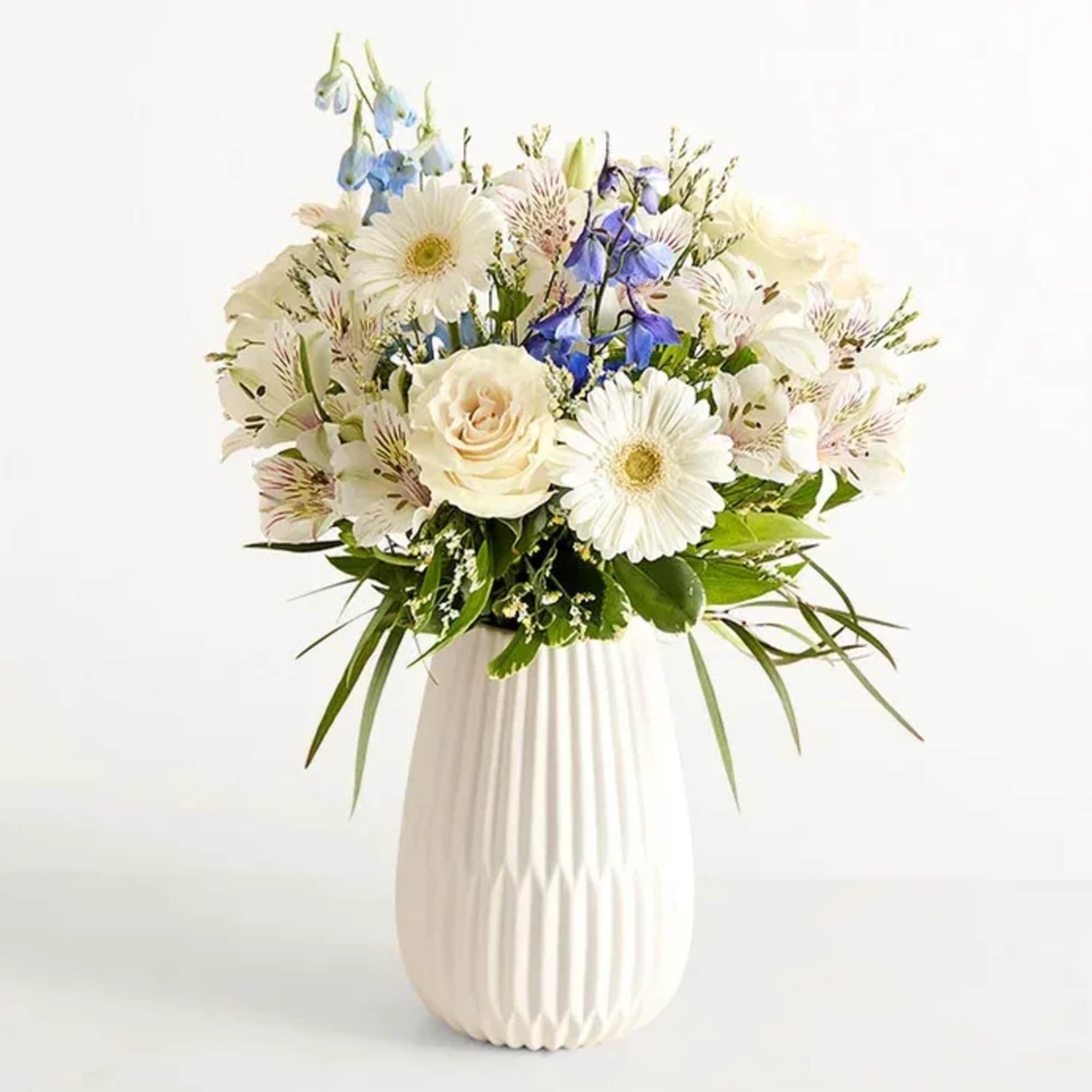 Soft white roses mingle with pale alstroemeria and cool blue delphinium to