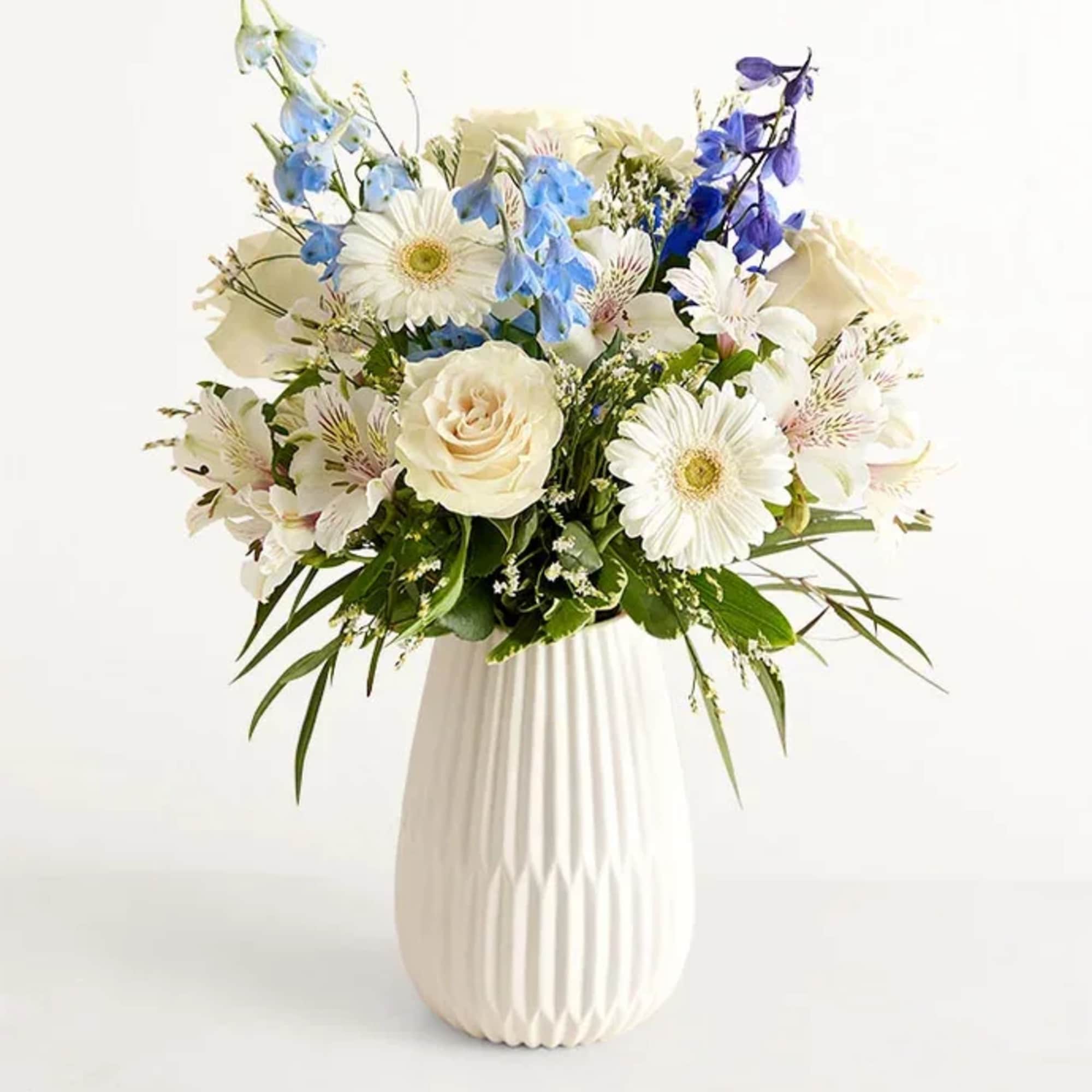 Soft white roses mingle with pale alstroemeria and cool blue delphinium to